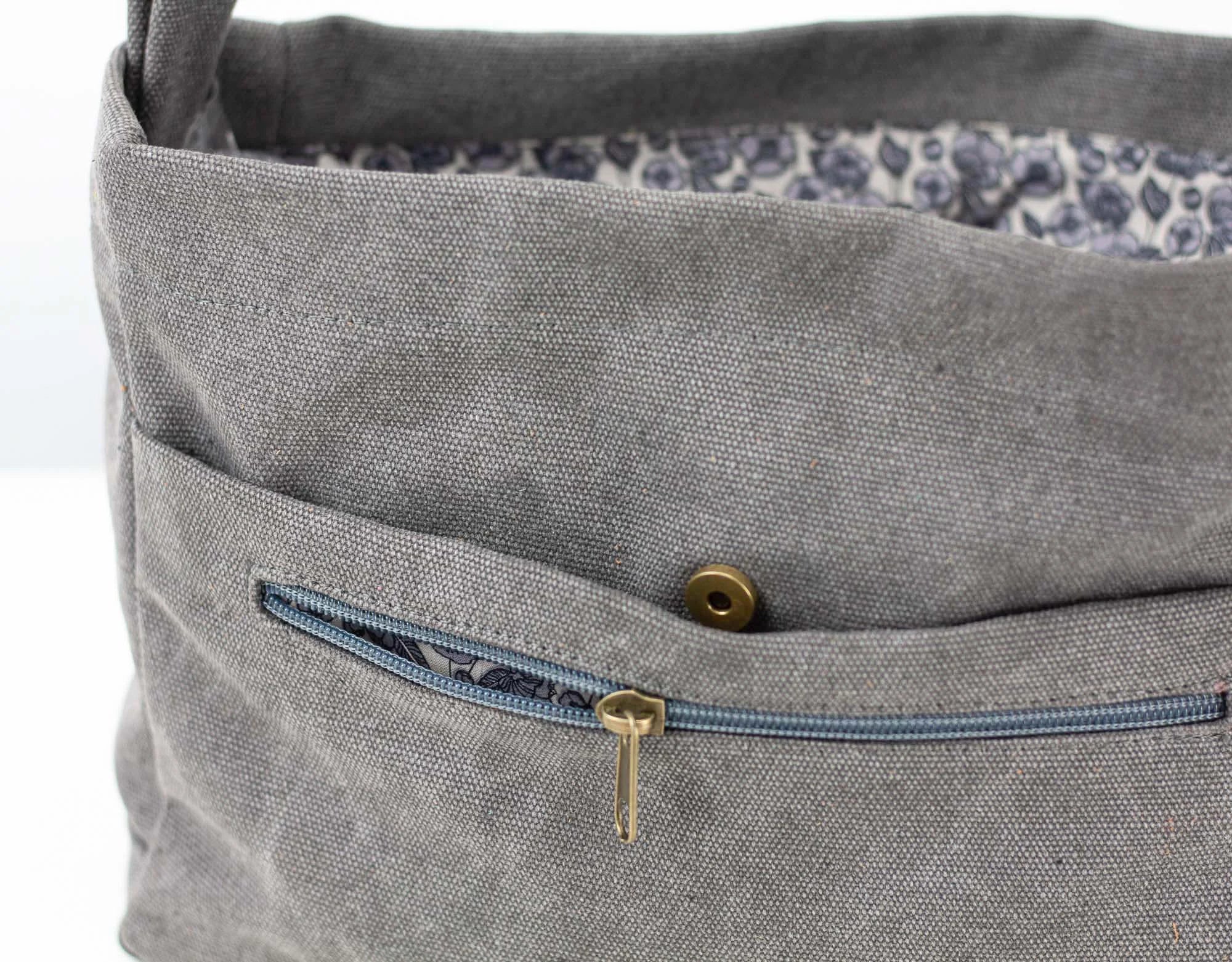 Gray fabric bag insert with a zipper pocket and floral lining on a white background