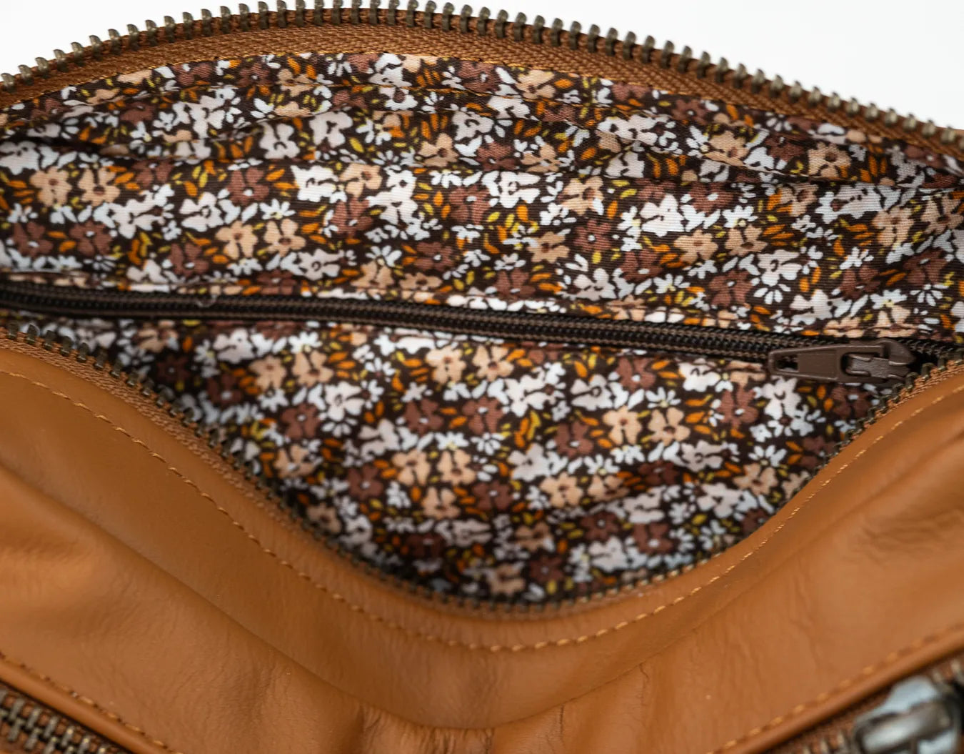 Close-up of a brown leather bag with a floral patterned interior.