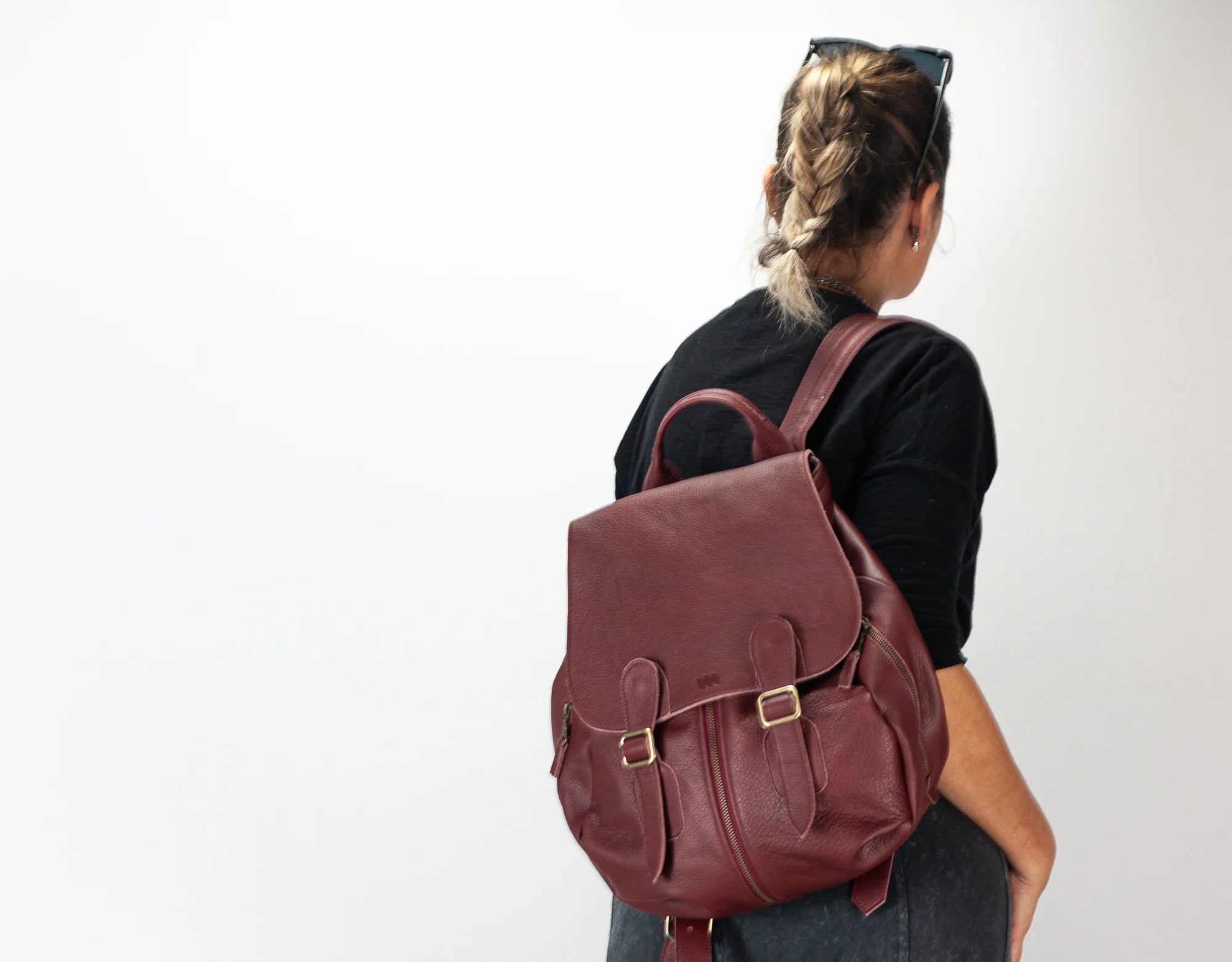Person wearing a brown leather backpack against a white background