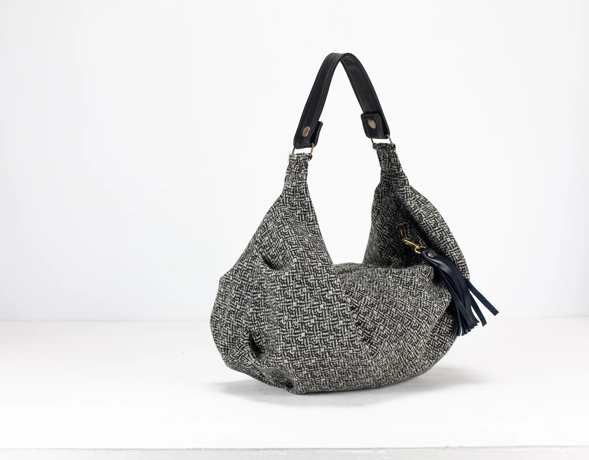 Gray textured handbag with a black strap on a white background