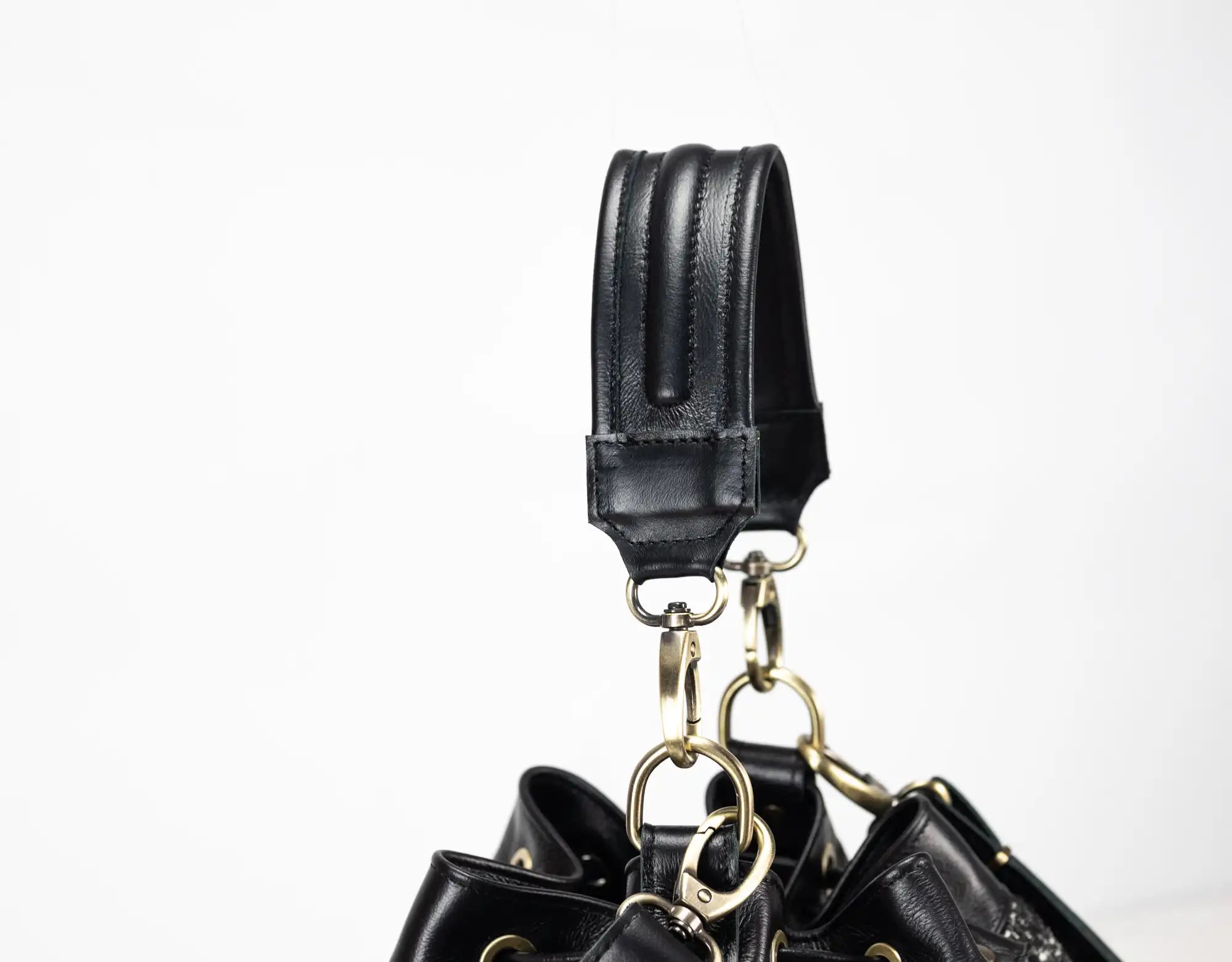 Black leather handbag with gold hardware on a white background