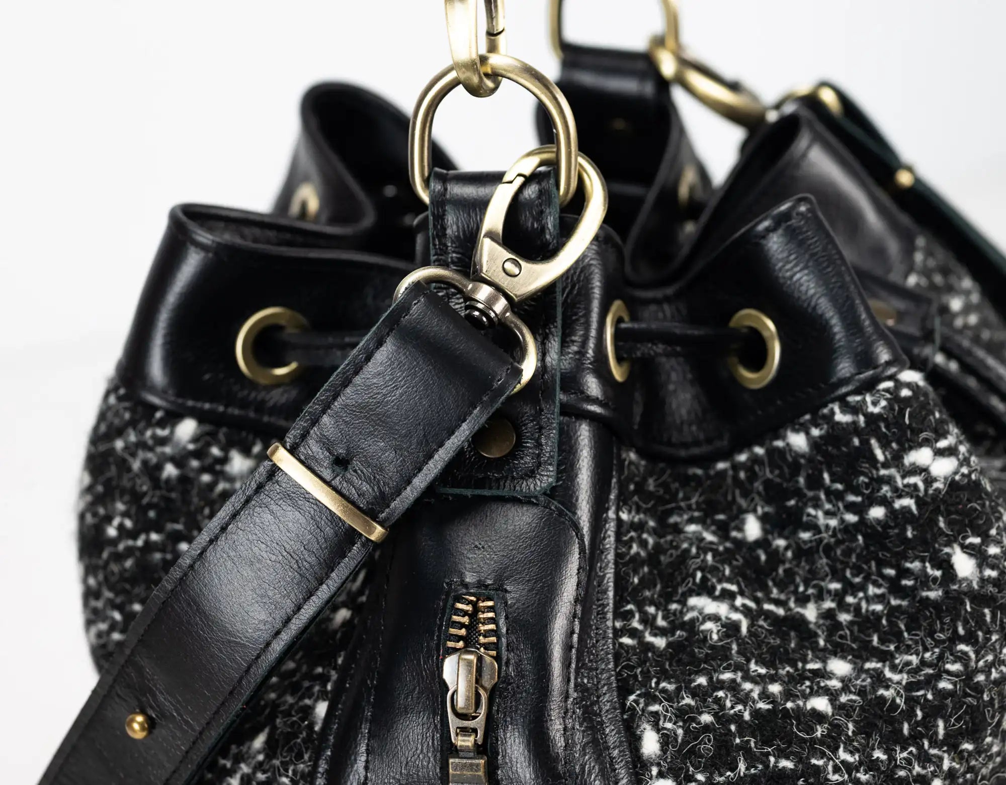 Black textured handbag with gold accents on a light gray background