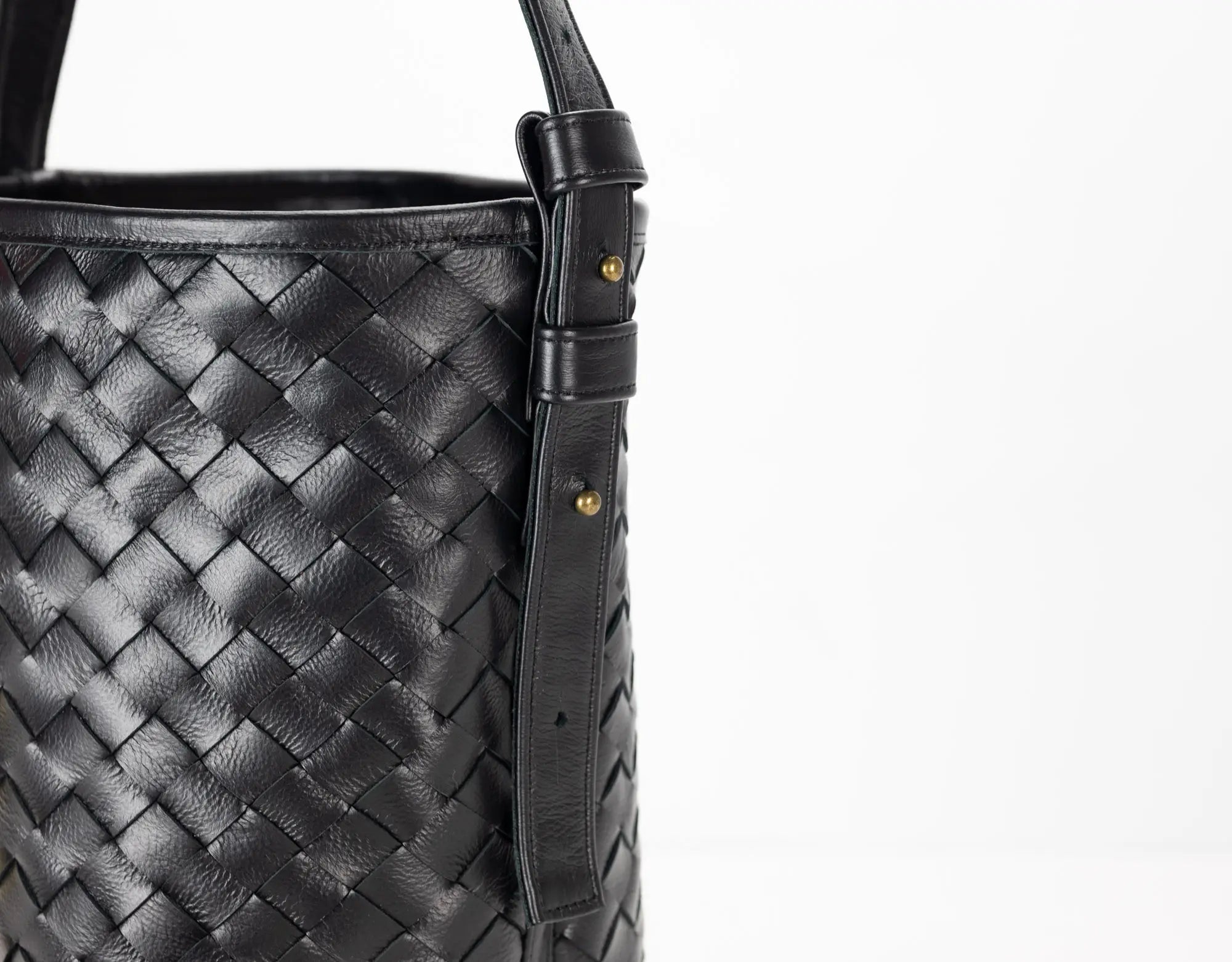 Black woven leather handbag with a strap on a white background