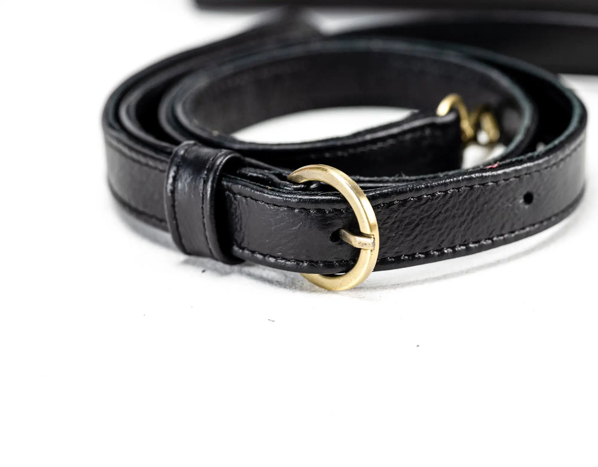 Black leather belt with a gold buckle on a white background