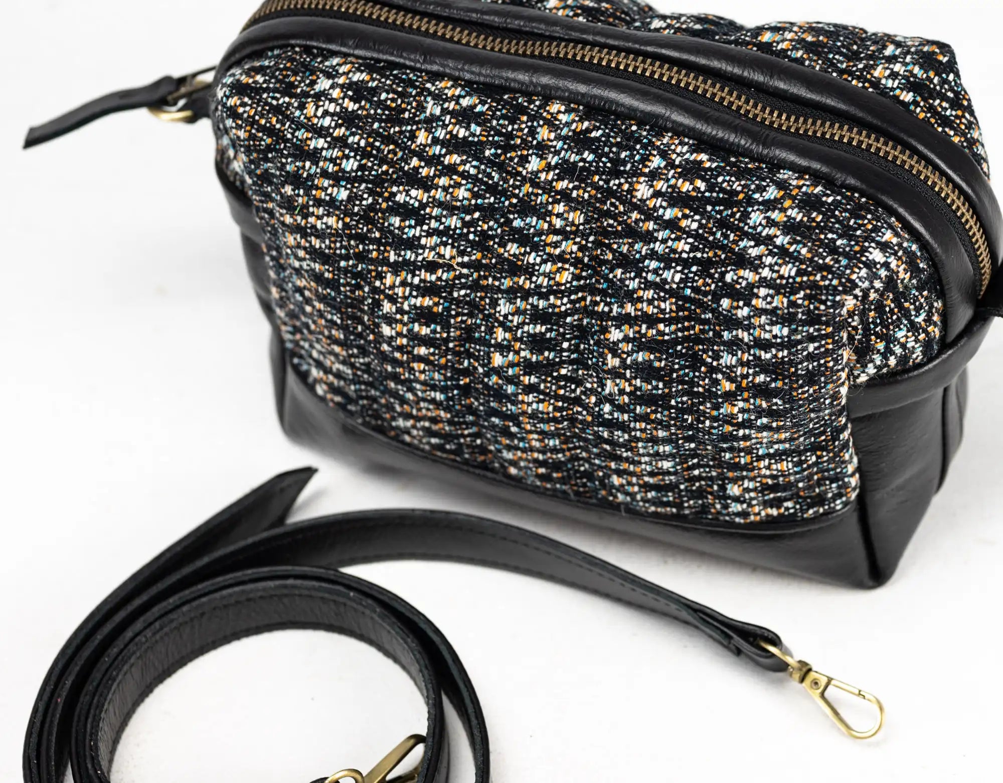 Black and gold patterned handbag with a strap on a white background