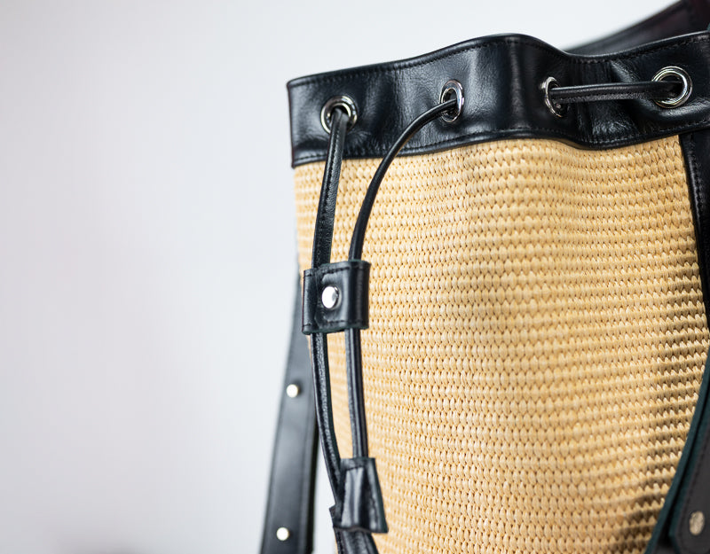 Close-up of a straw hat with black leather straps on a light gray background