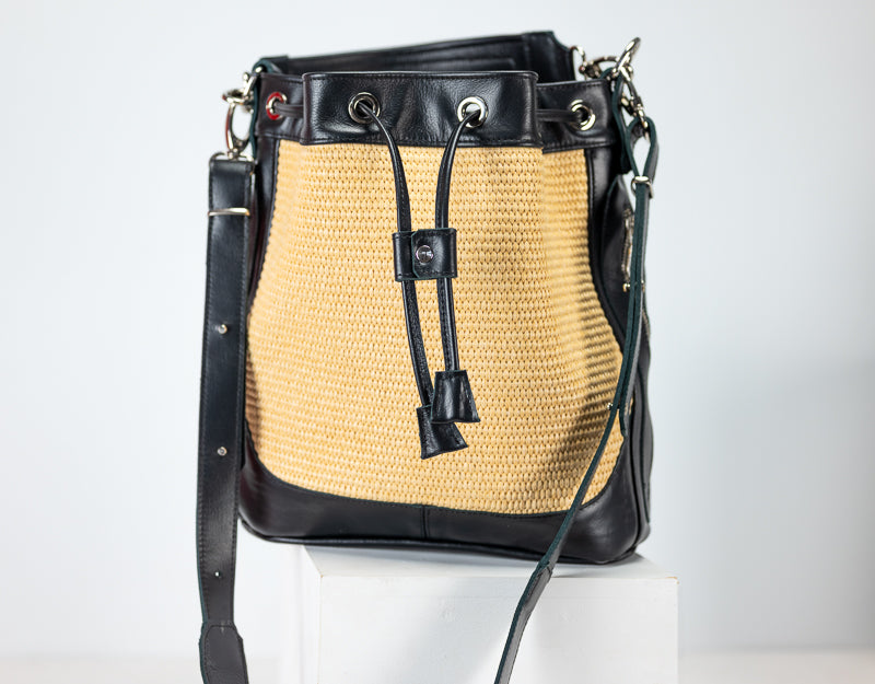 Handbag with straw pattern and black leather accents on a white background