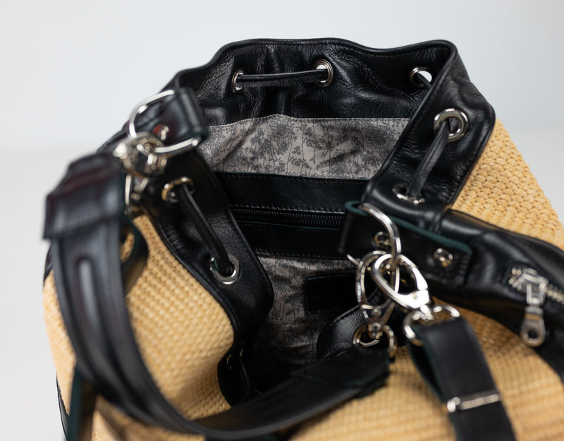 Close-up of a black leather bag with a beige exterior on a light gray background