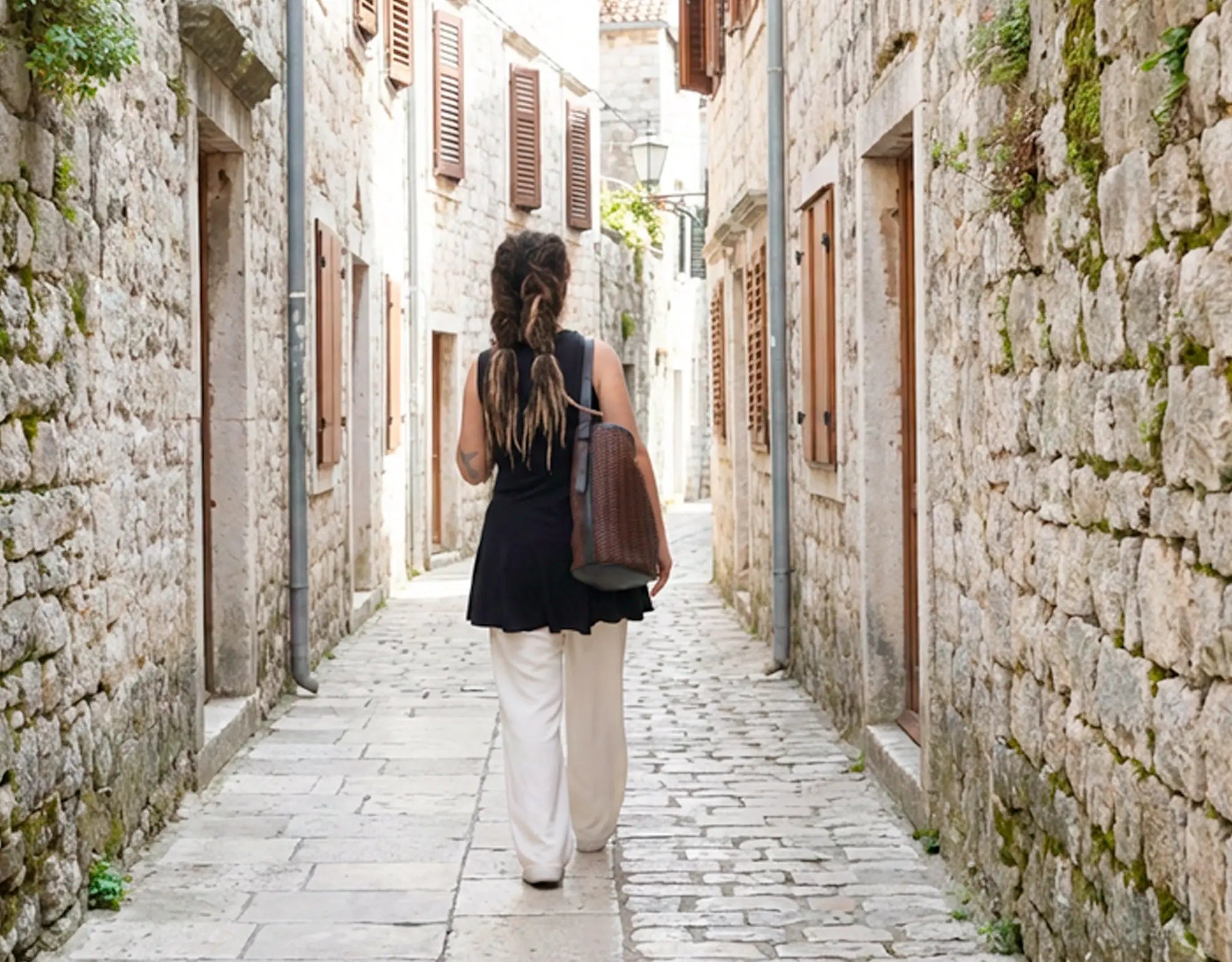 Woman walking down a narrow stone alleyway in an old town.