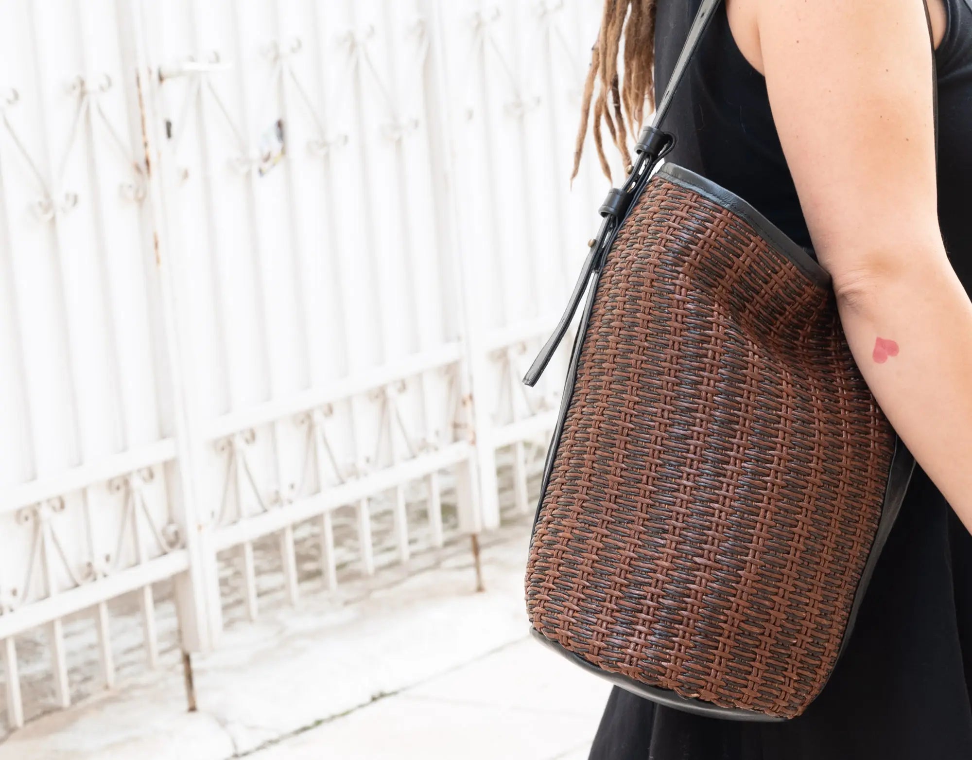Person holding a woven handbag with a blurred white background