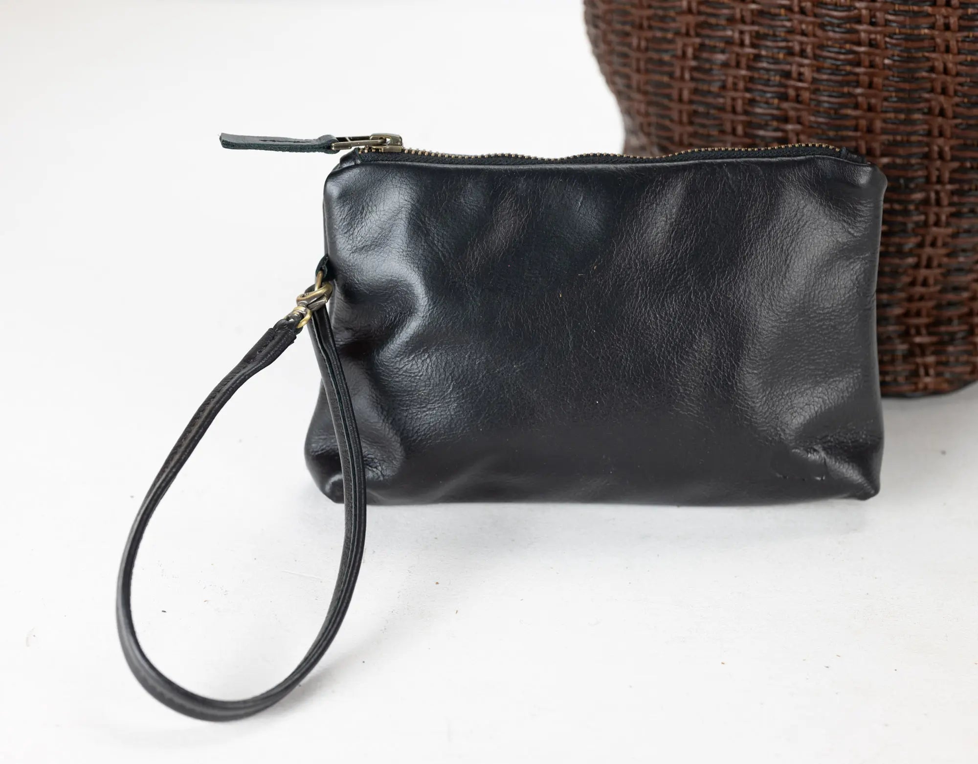Black leather clutch with wrist strap on a white background