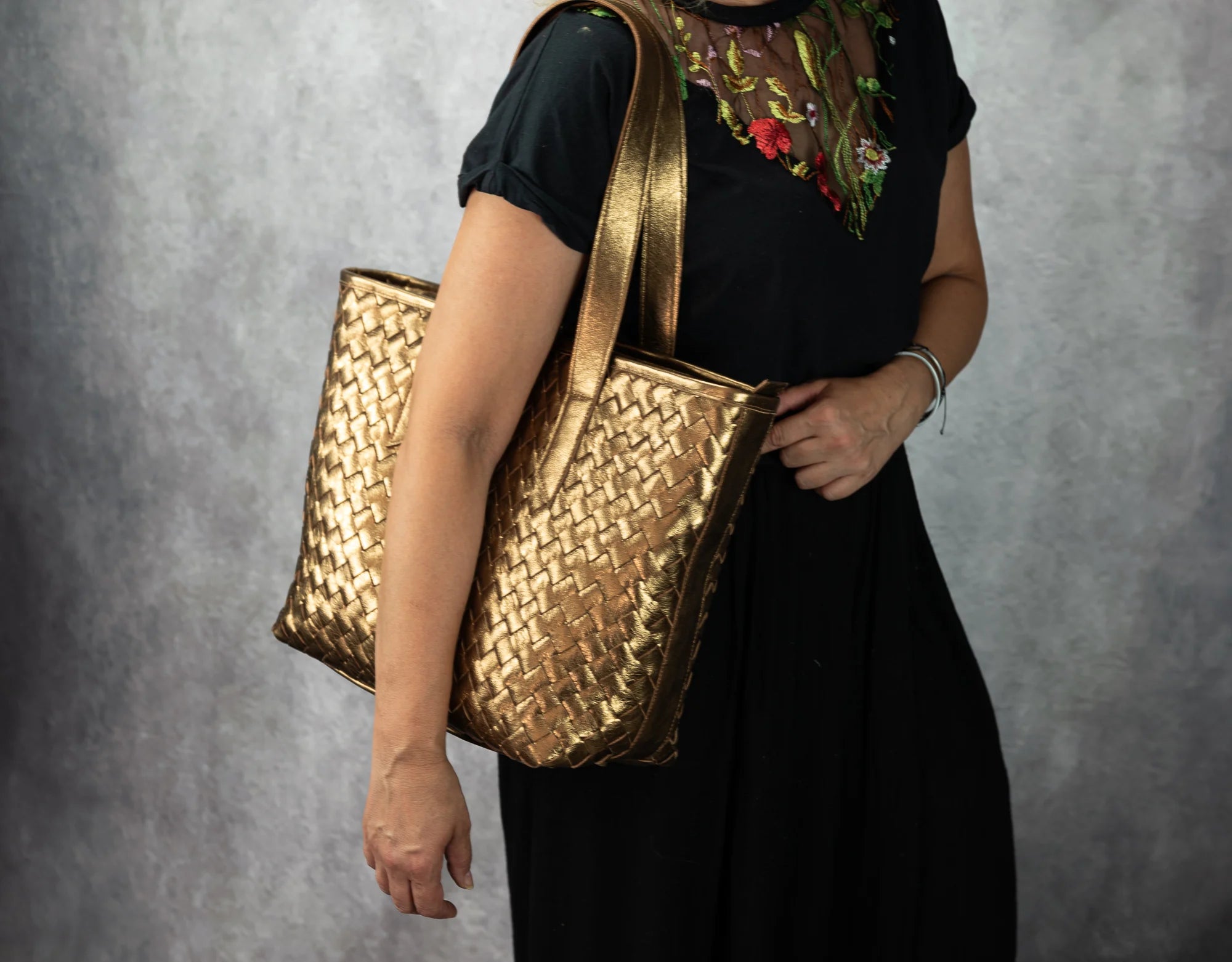 Person holding a gold woven handbag
