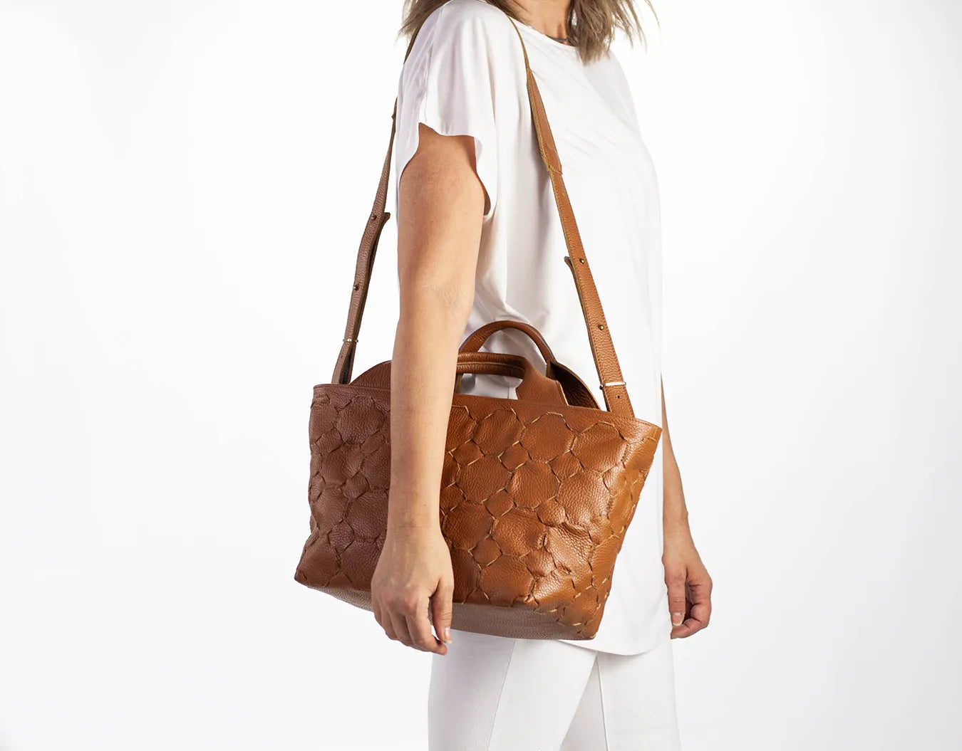 Person holding a brown textured handbag on a white background