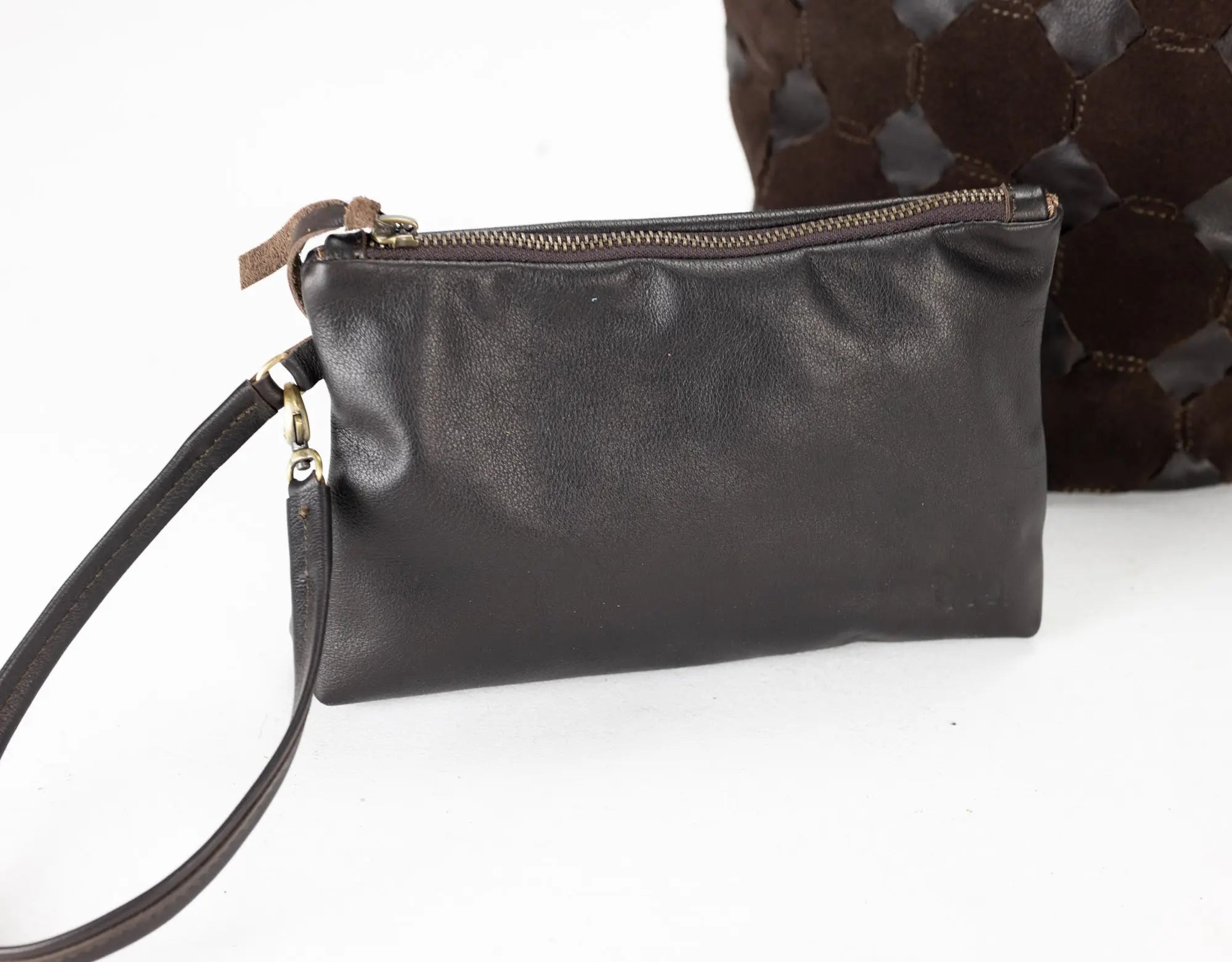 Black leather clutch bag with a strap on a white background