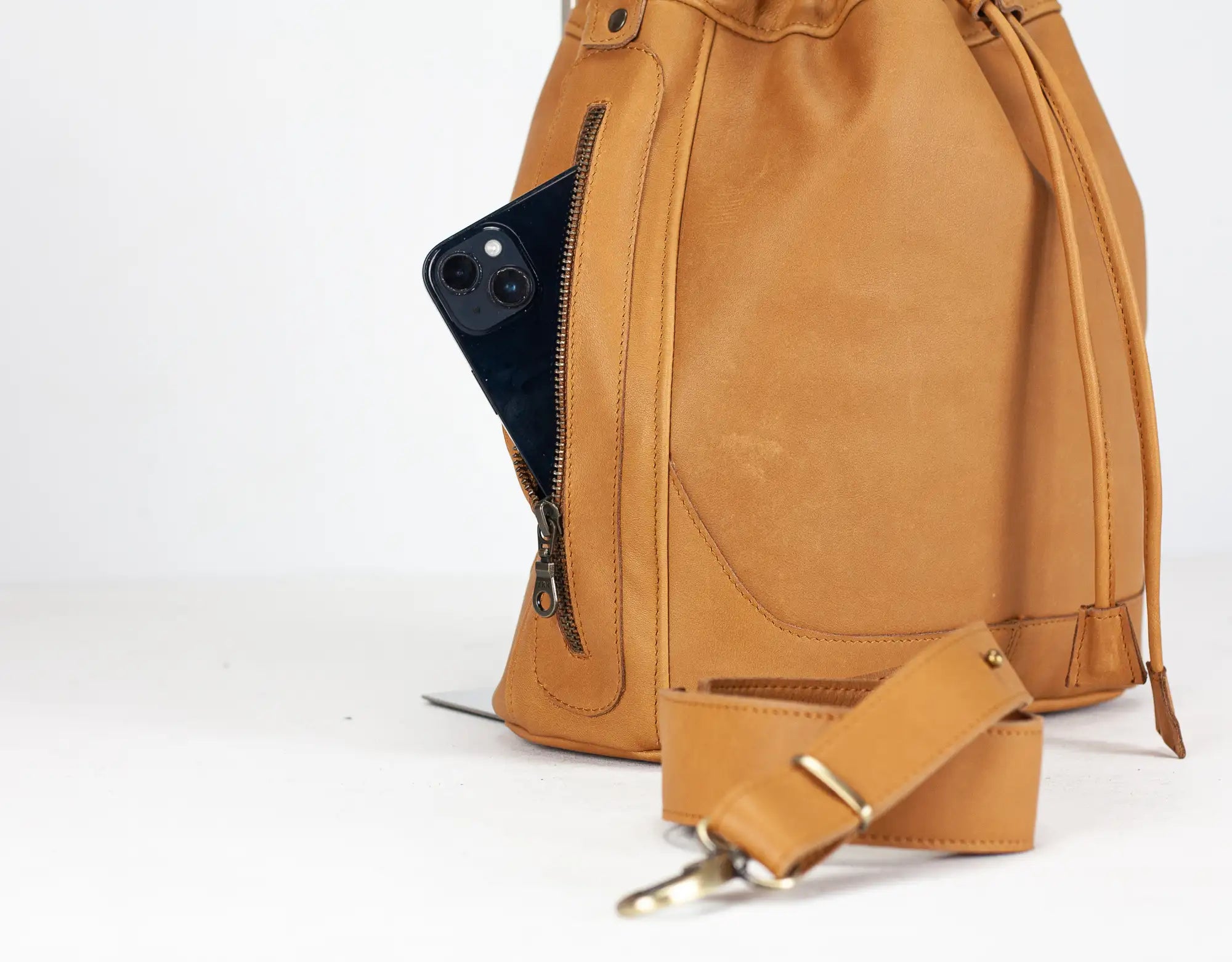 Brown leather backpack with a phone in a pocket on a white background