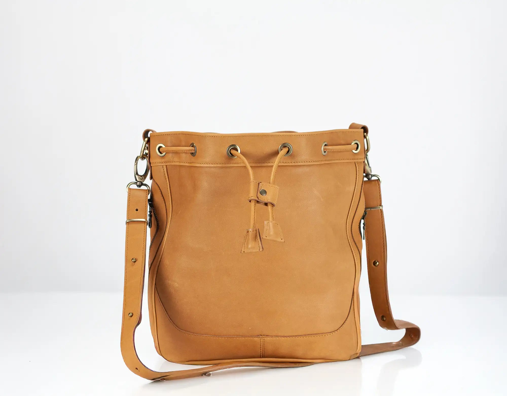 Tan leather handbag with drawstring on a white background