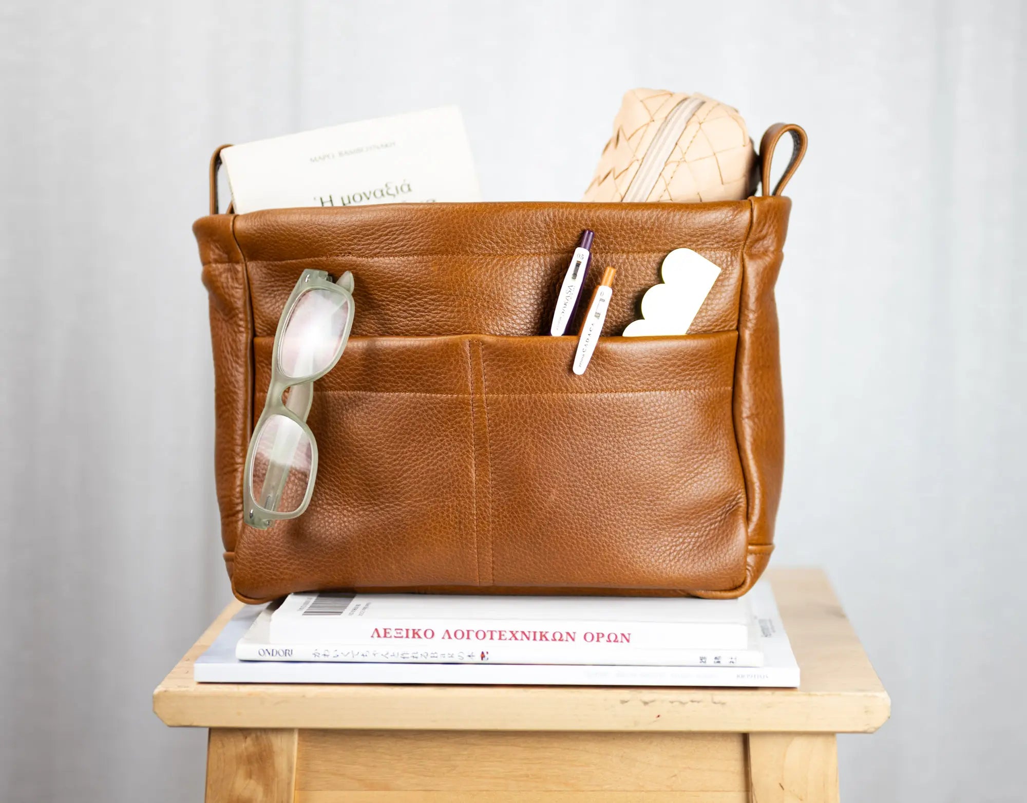 Brown leather bag with compartments on a wooden surface