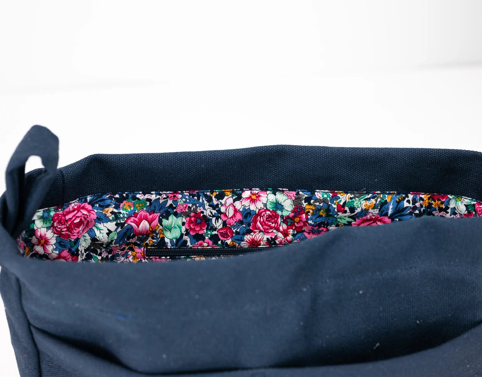 Navy blue bag with a floral patterned strap on a white background