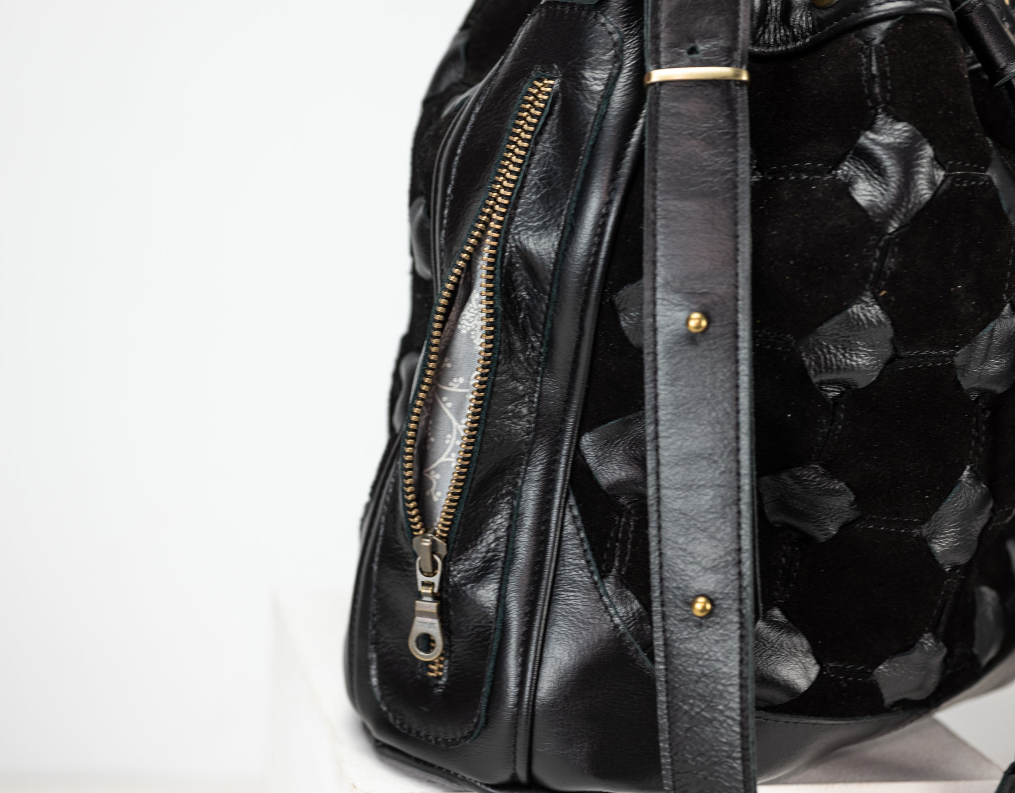 Black leather bag with floral pattern on a white background