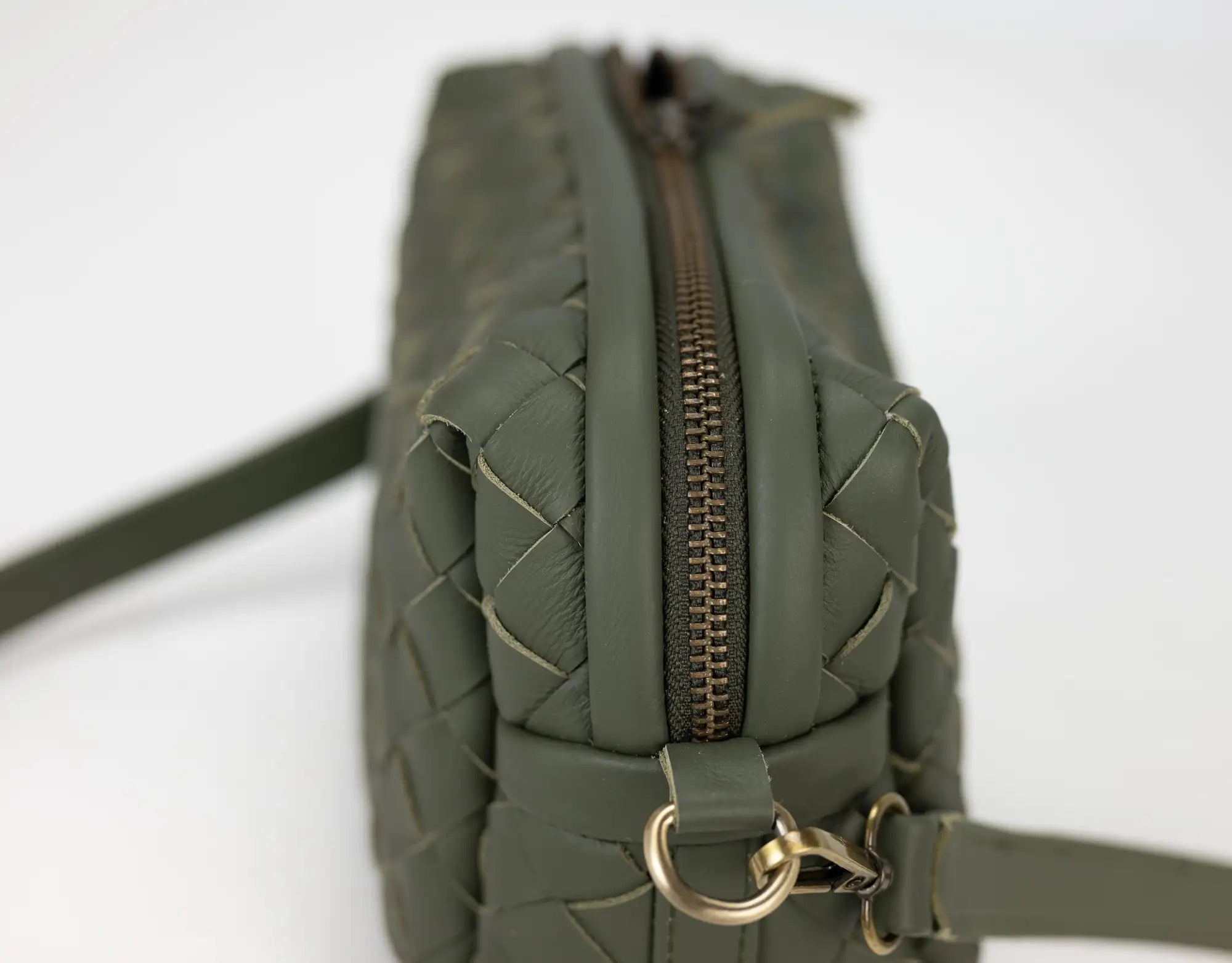Green quilted handbag with a gold zipper on a white background