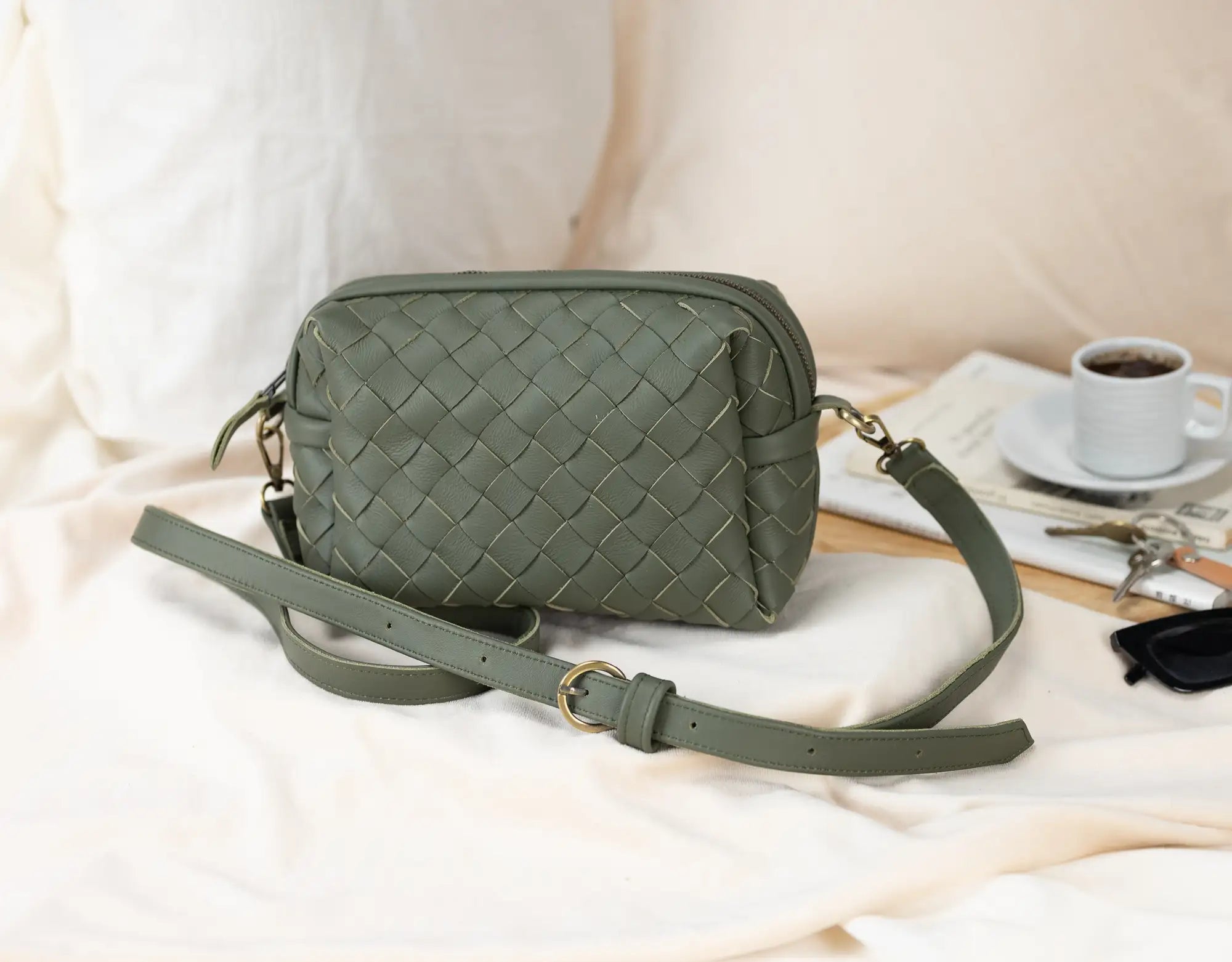 Green woven handbag on a light surface with a cup of coffee