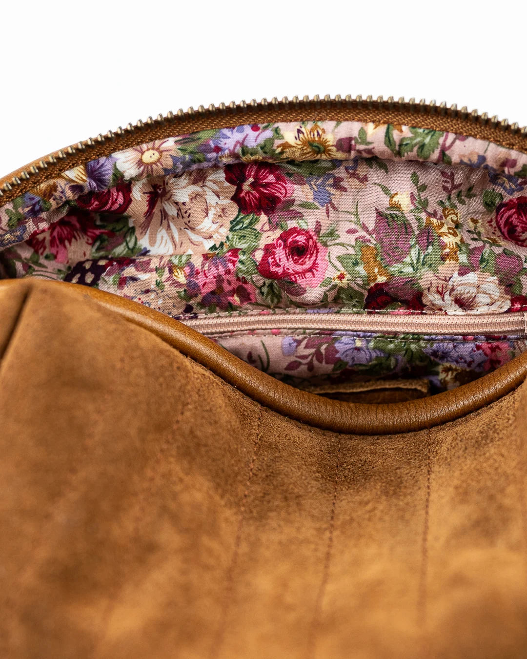Close-up of a brown leather bag with floral interior lining.