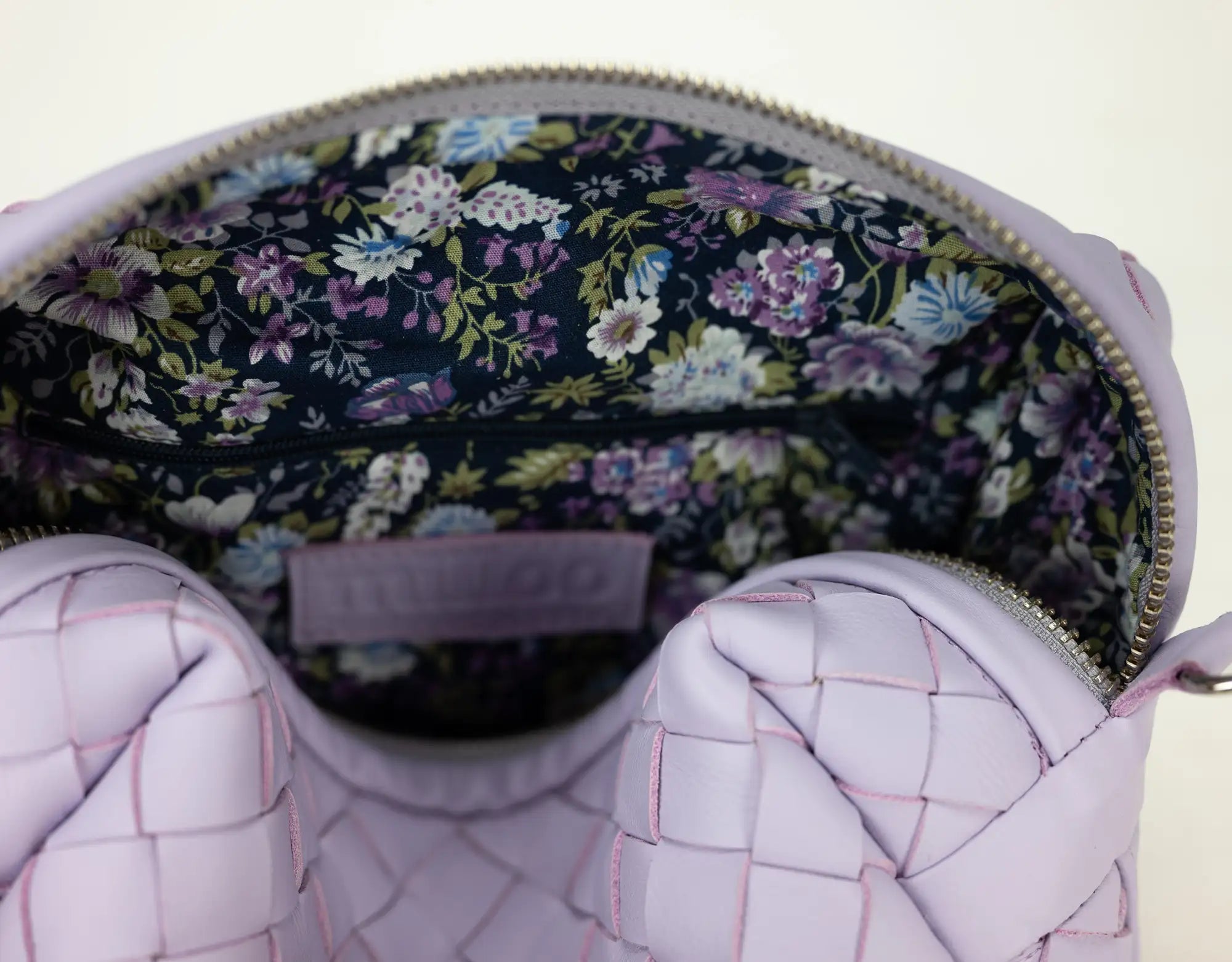 Pink quilted handbag with floral interior on a light background