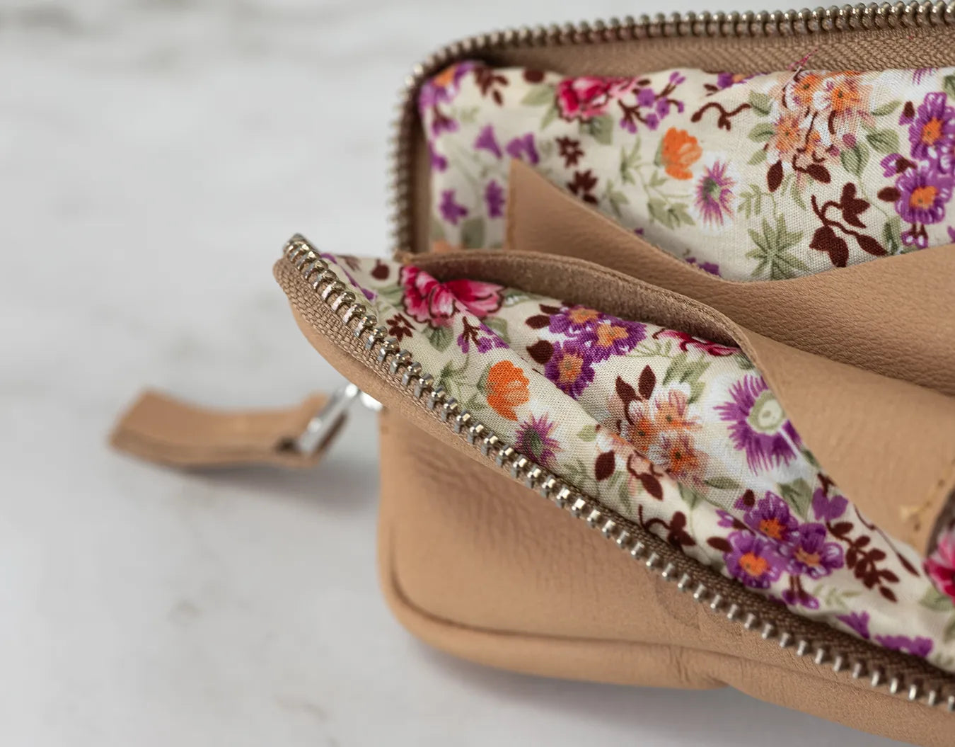 Close-up of a beige wallet with floral interior on a light gray background