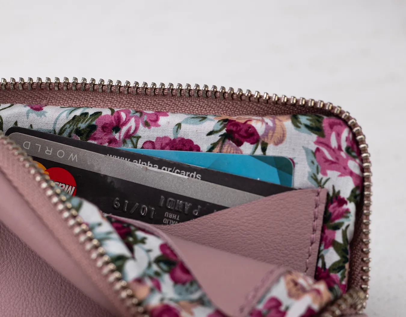Floral-patterned wallet with cards inside on a light pink background