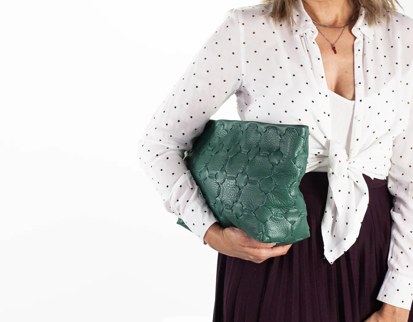 Woman holding a green clutch bag against a white background