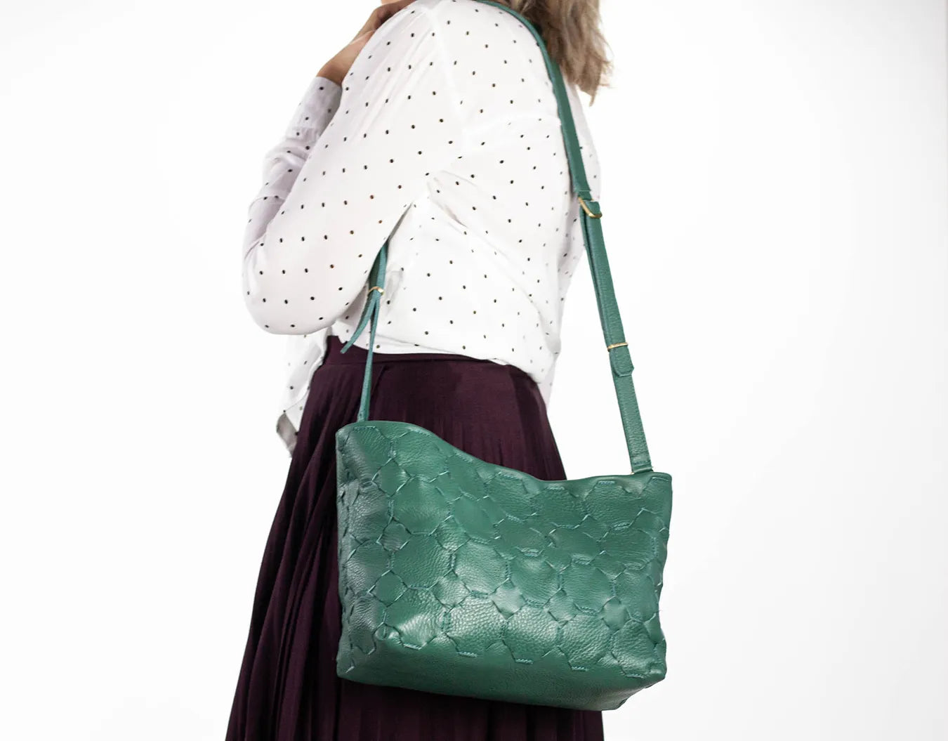 Green handbag worn by a person on a white background