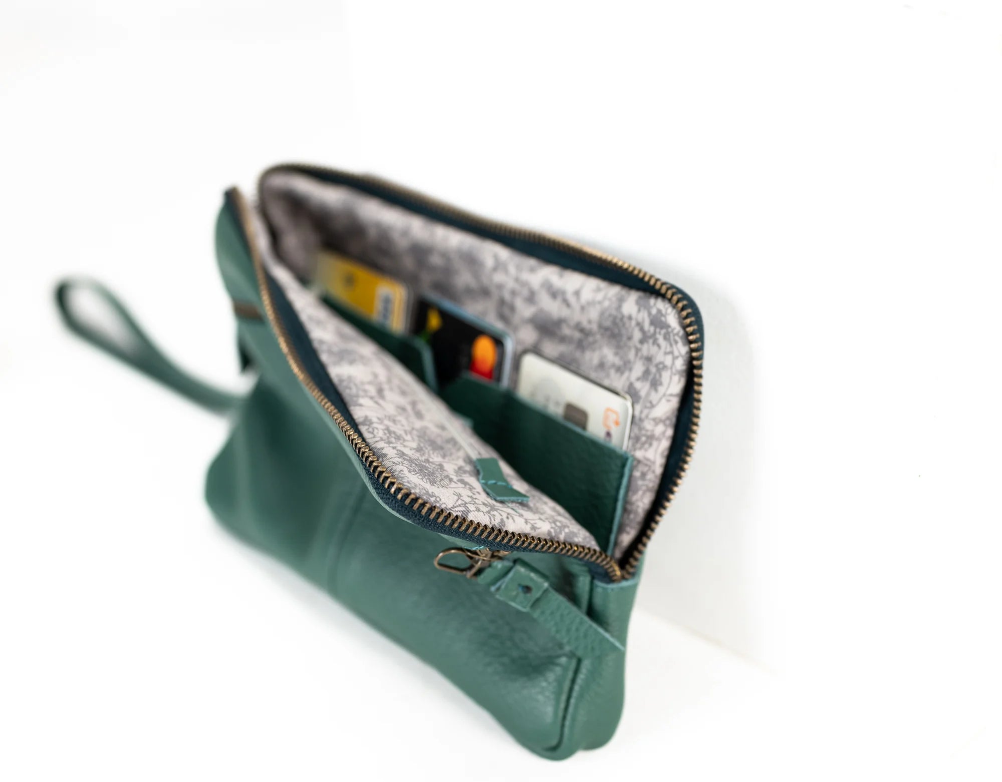 Green clutch bag with open zipper showing interior on a white background