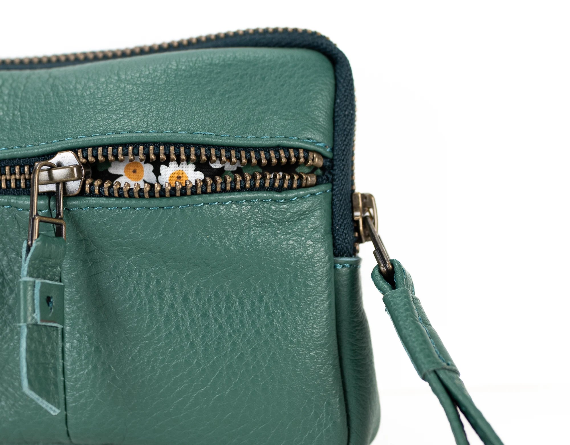 Green leather handbag with a zipper and decorative flowers on a white background