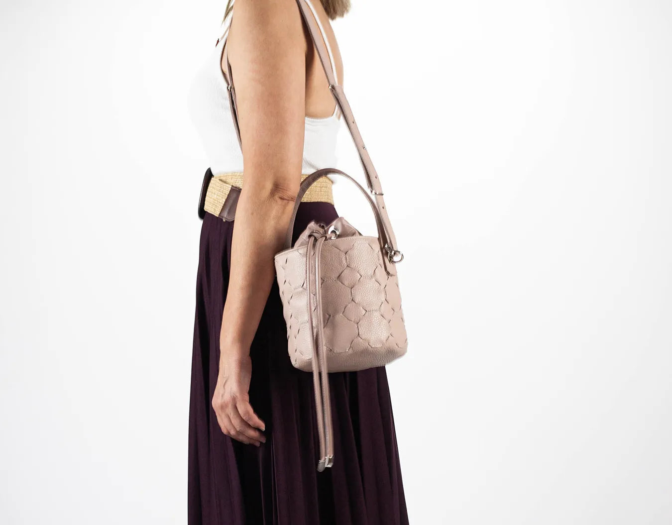 Woman holding a beige handbag against a white background