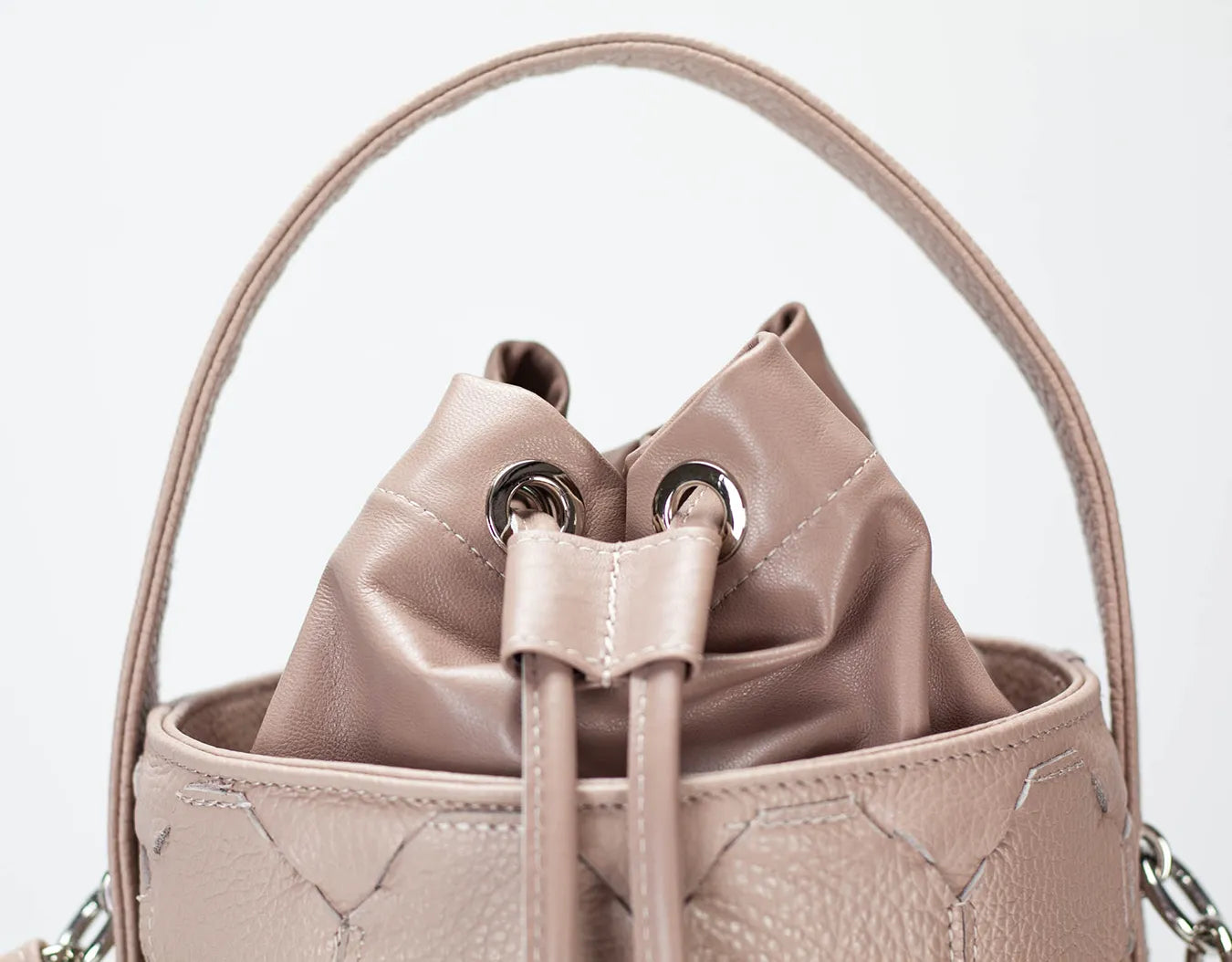 Beige leather bucket bag with drawstring on a light gray background