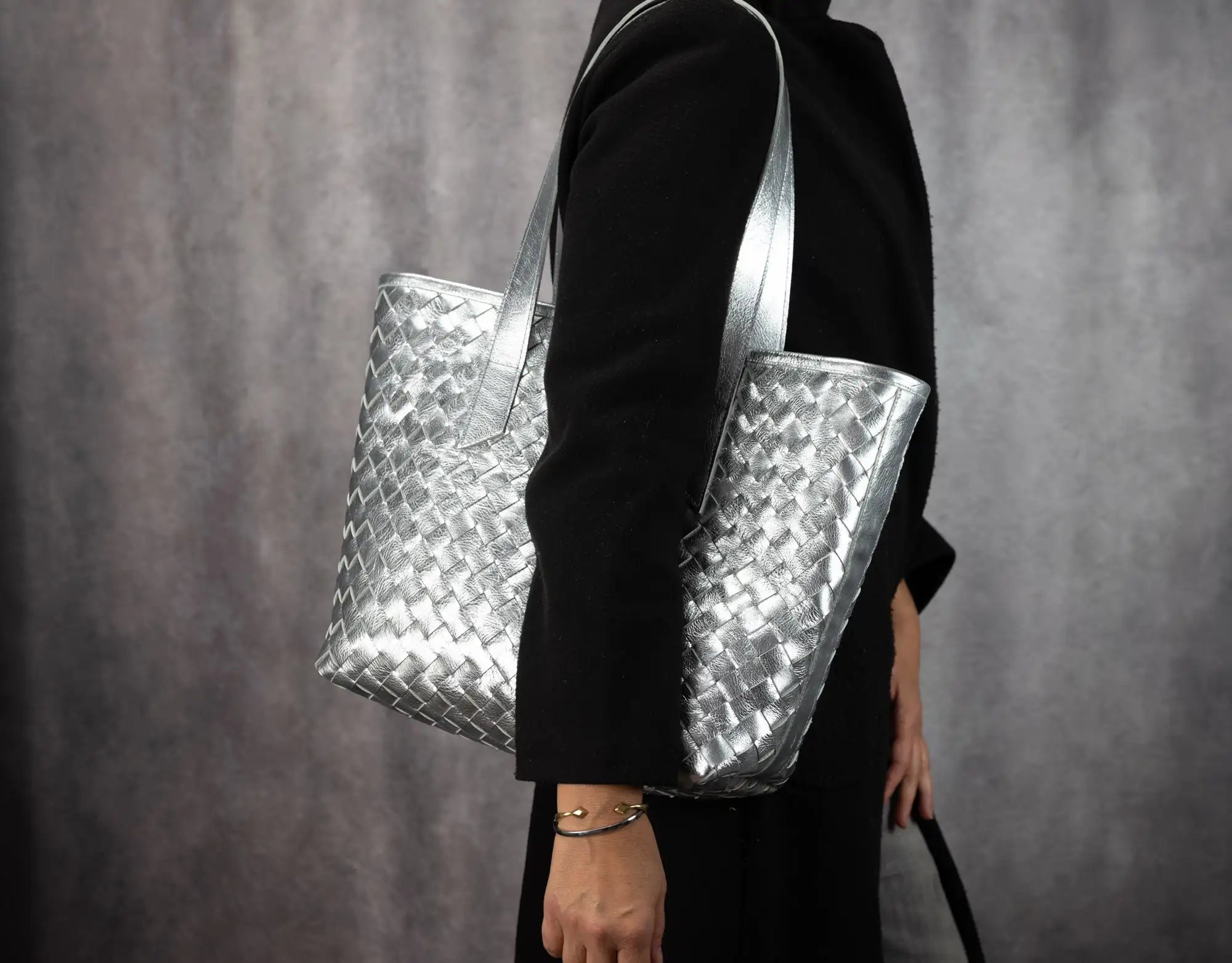 Person holding a silver woven handbag