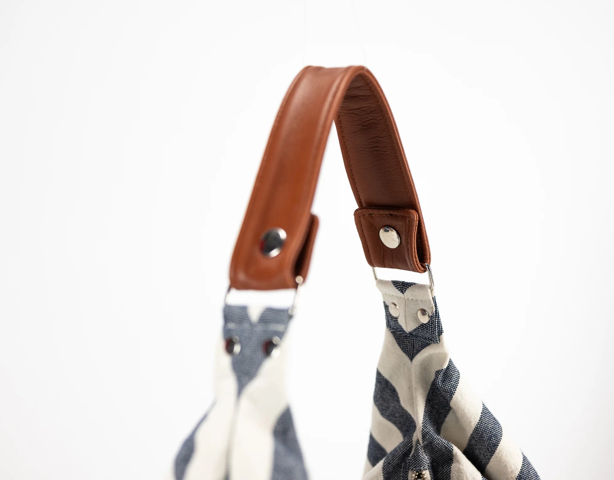 Striped bag with a brown leather strap on a white background