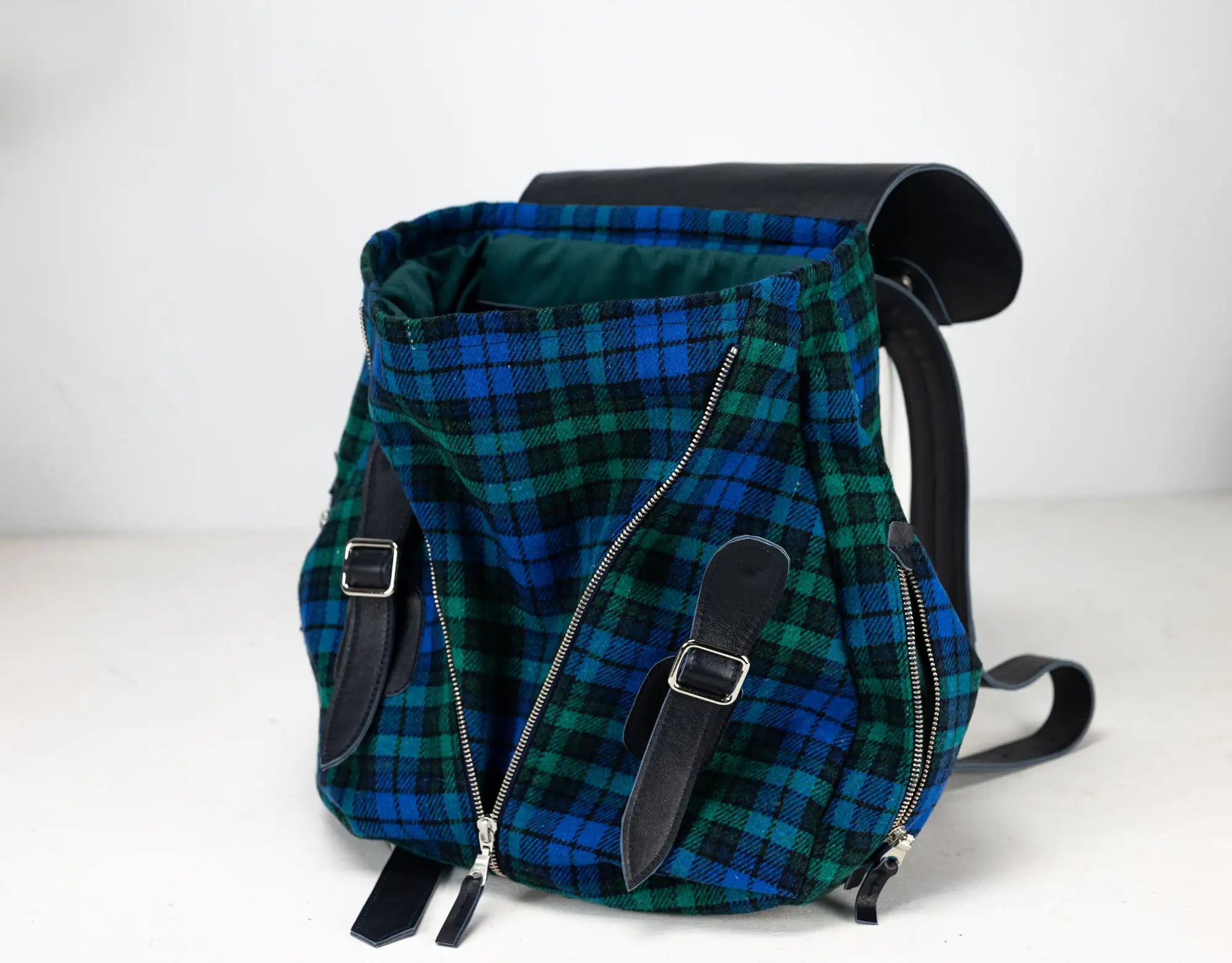 Blue and green plaid backpack with black straps on a white background