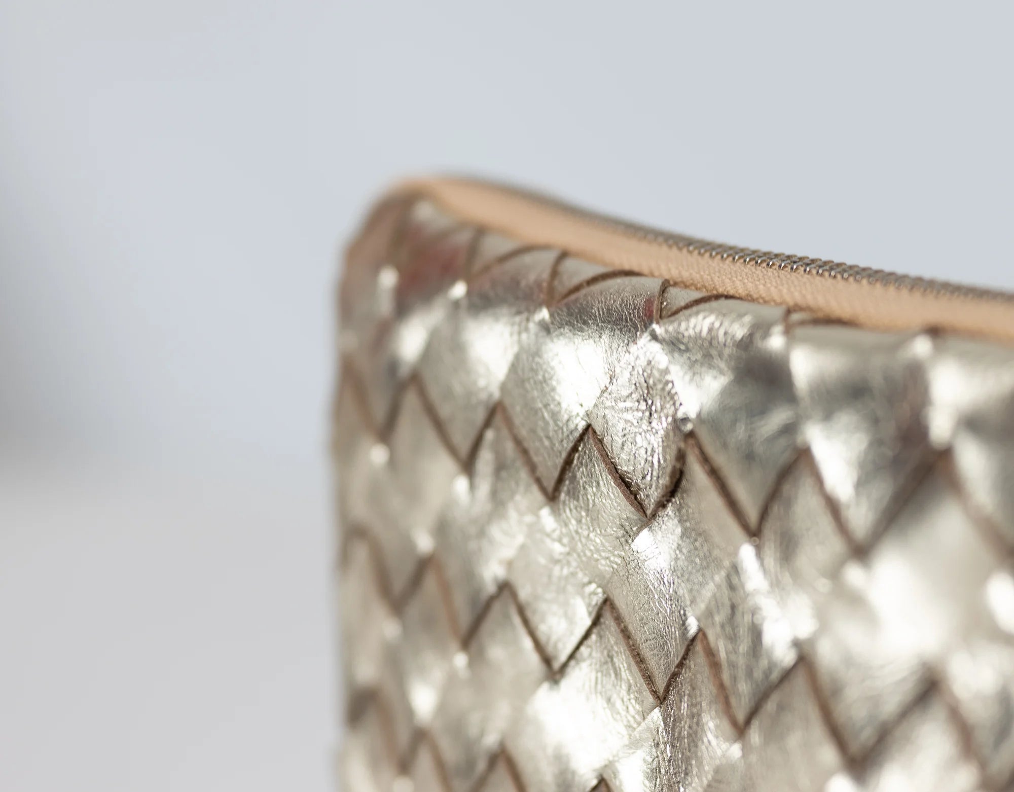 Close-up of a metallic textured clutch bag on a light gray background