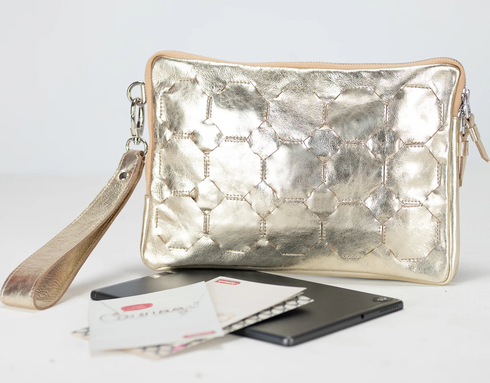 Yellow gold quilted clutch bag with a phone and cards on a white background