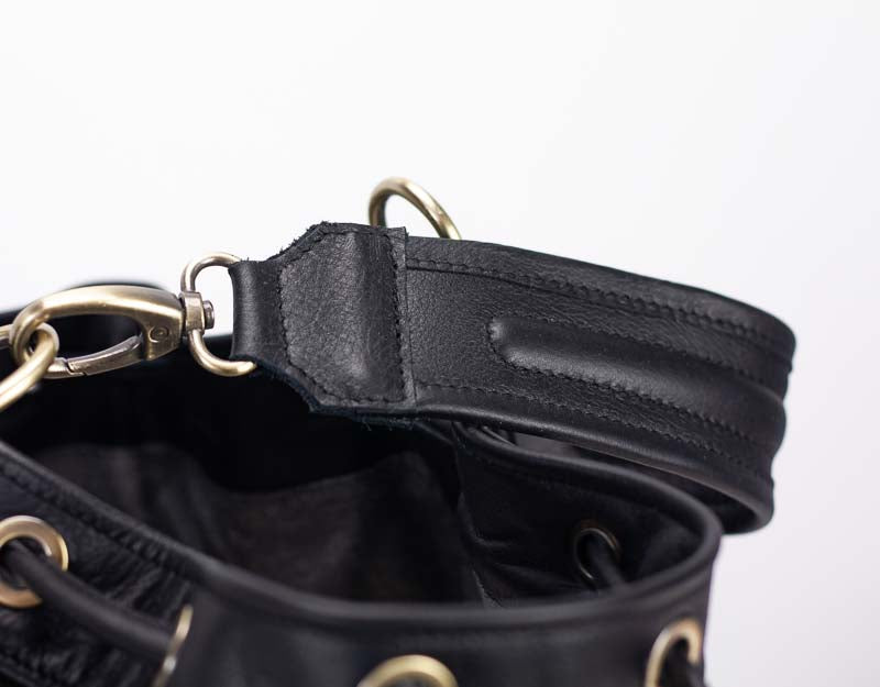 Close-up of a black leather bag with gold hardware on a white background
