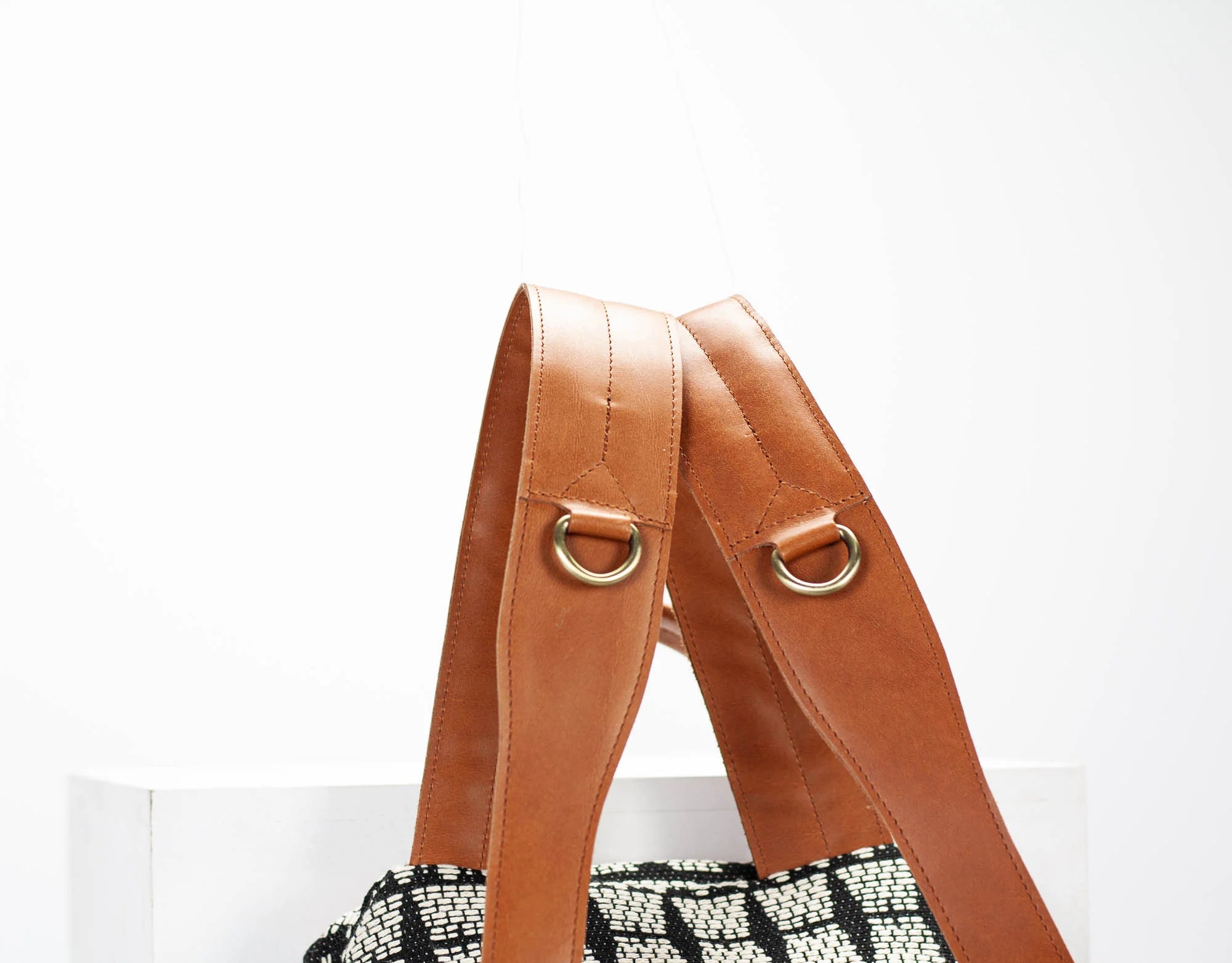 Brown leather bag strap with gold hardware on a white background
