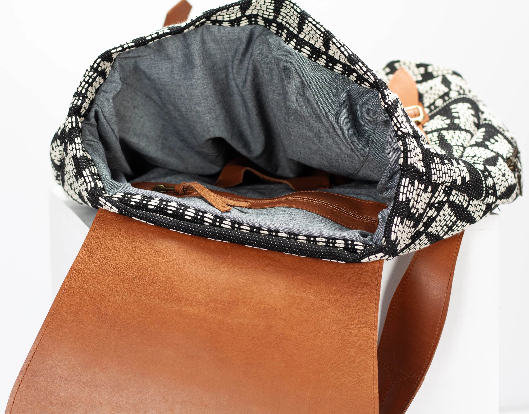 Brown leather bag with patterned flap on a white background