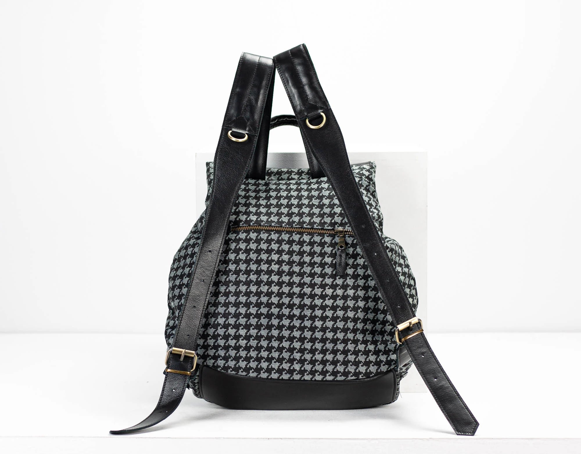 Backpack with houndstooth pattern and black straps on a white background