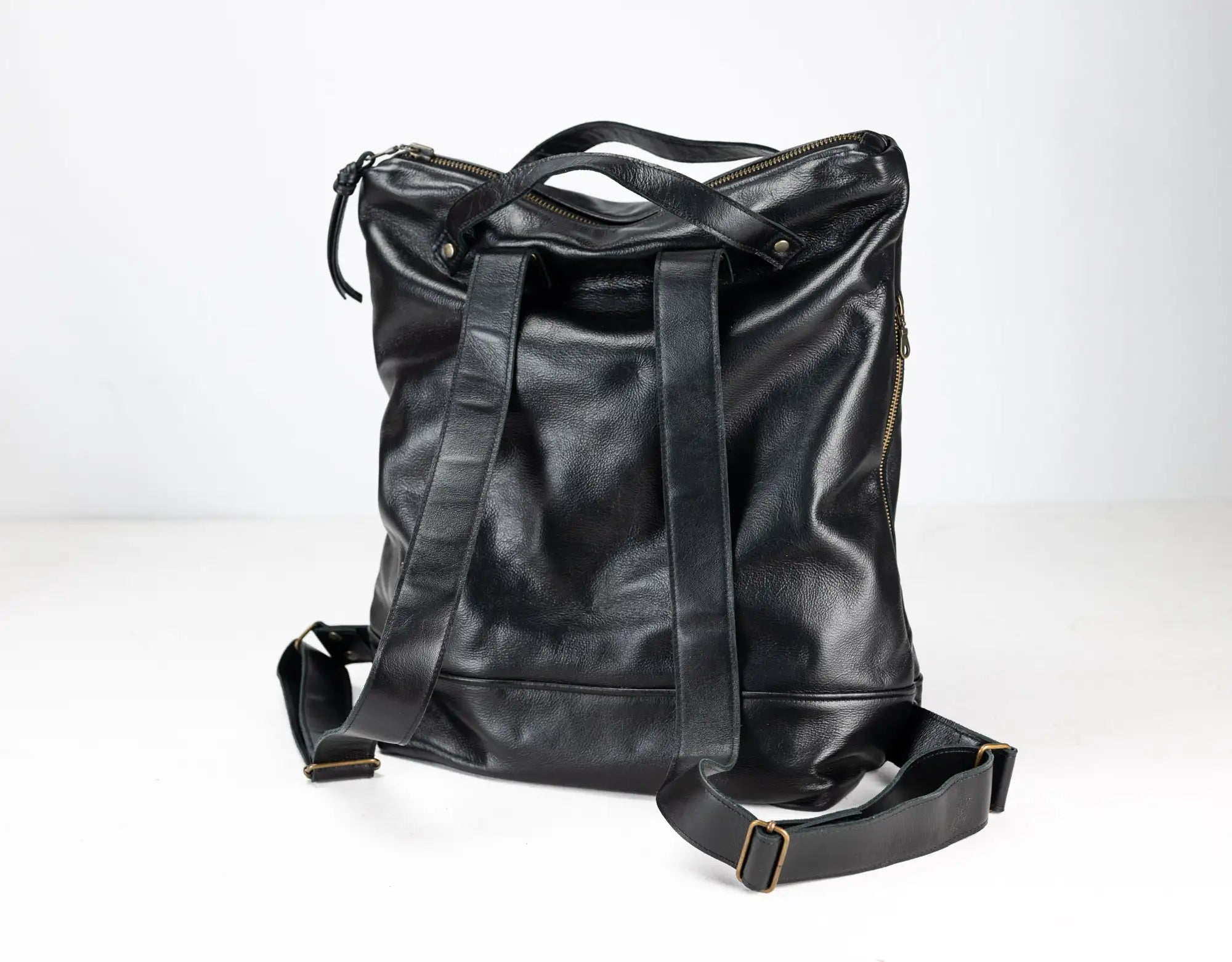 Black leather bag with multiple straps on a white background