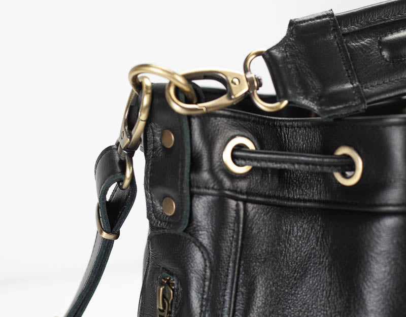 Close-up of a black leather bag with gold hardware on a white background