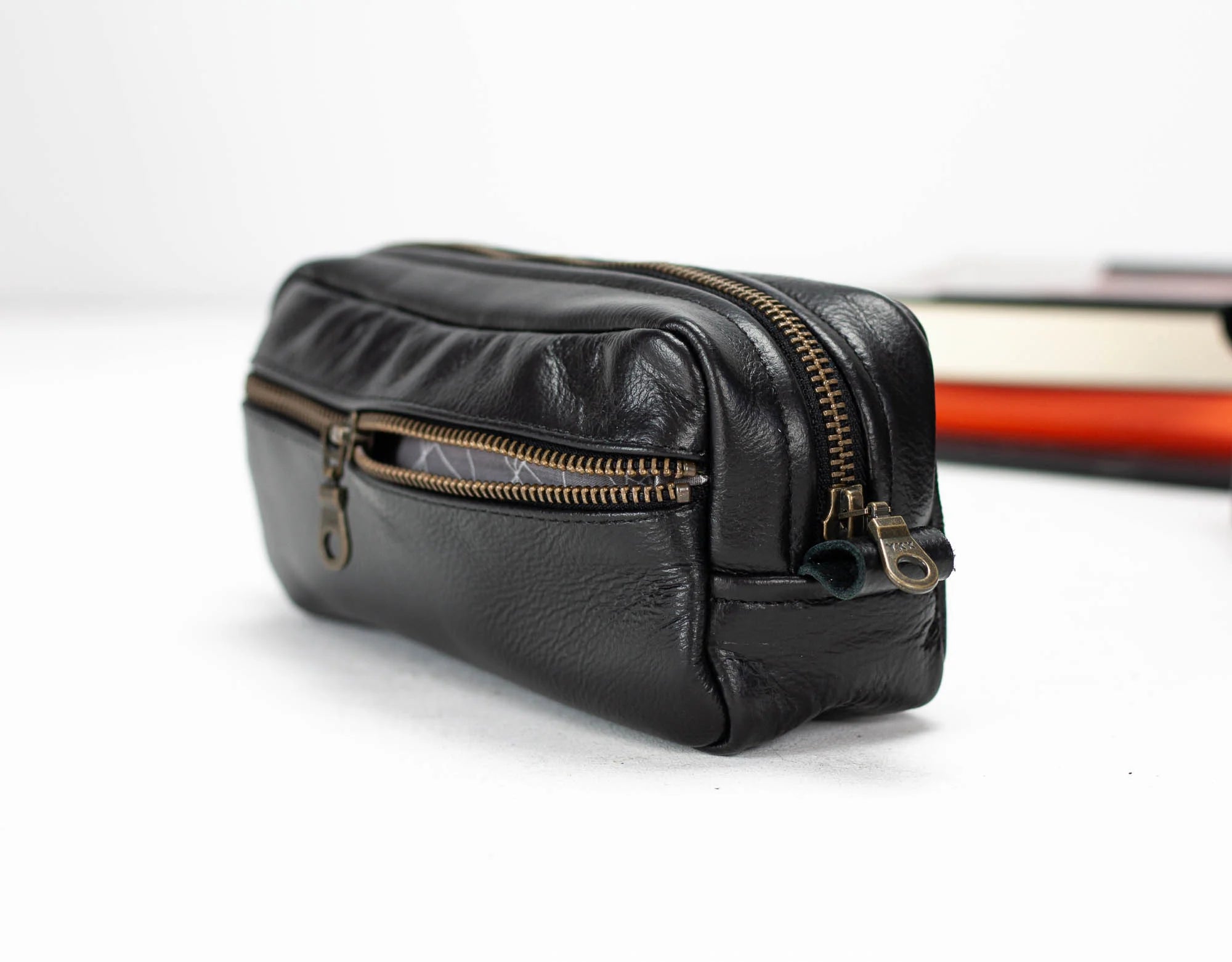 Black leather pouch with gold zippers on a white background