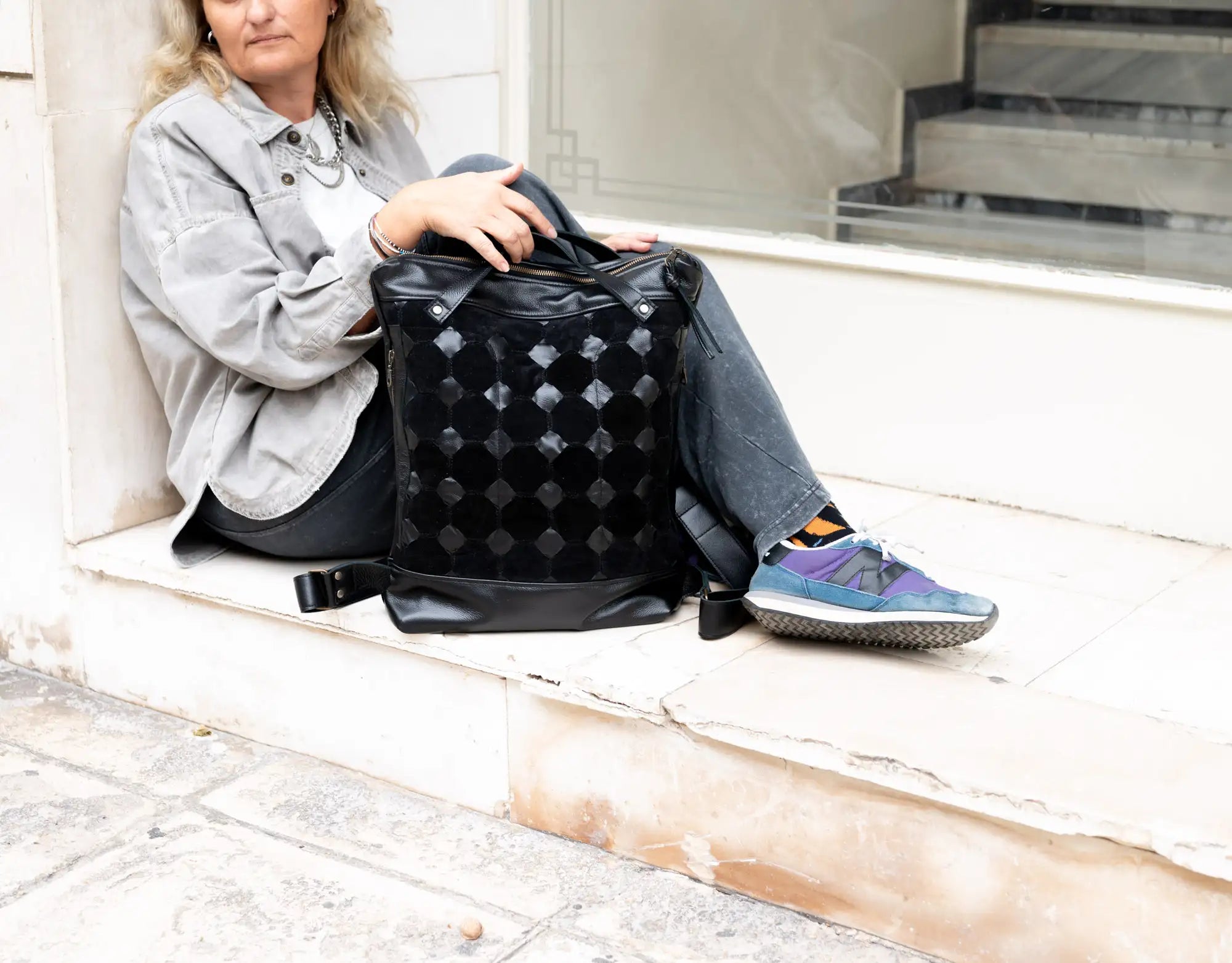 Person sitting on steps with a black patterned bag