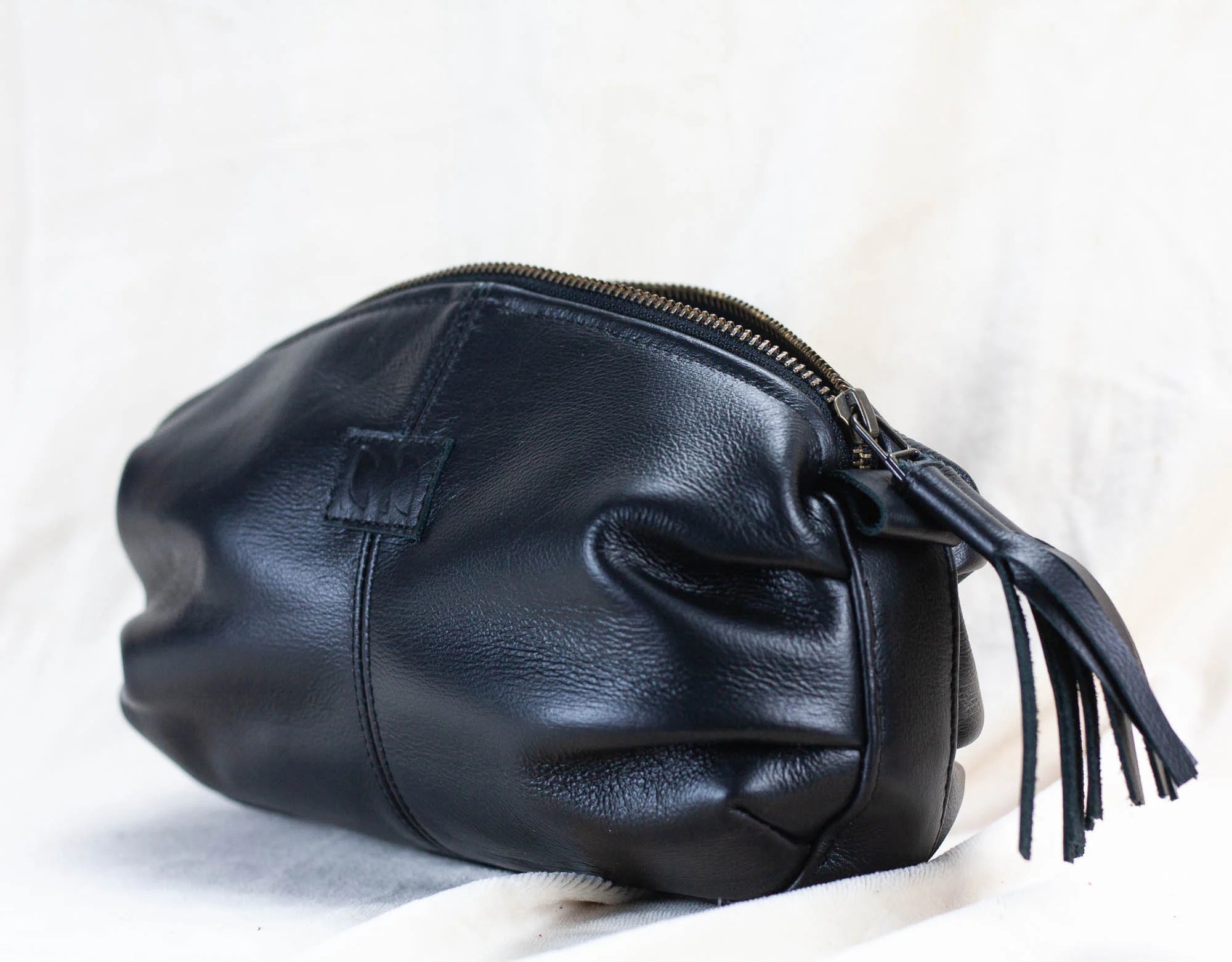 Black leather clutch bag with tassel on a light background