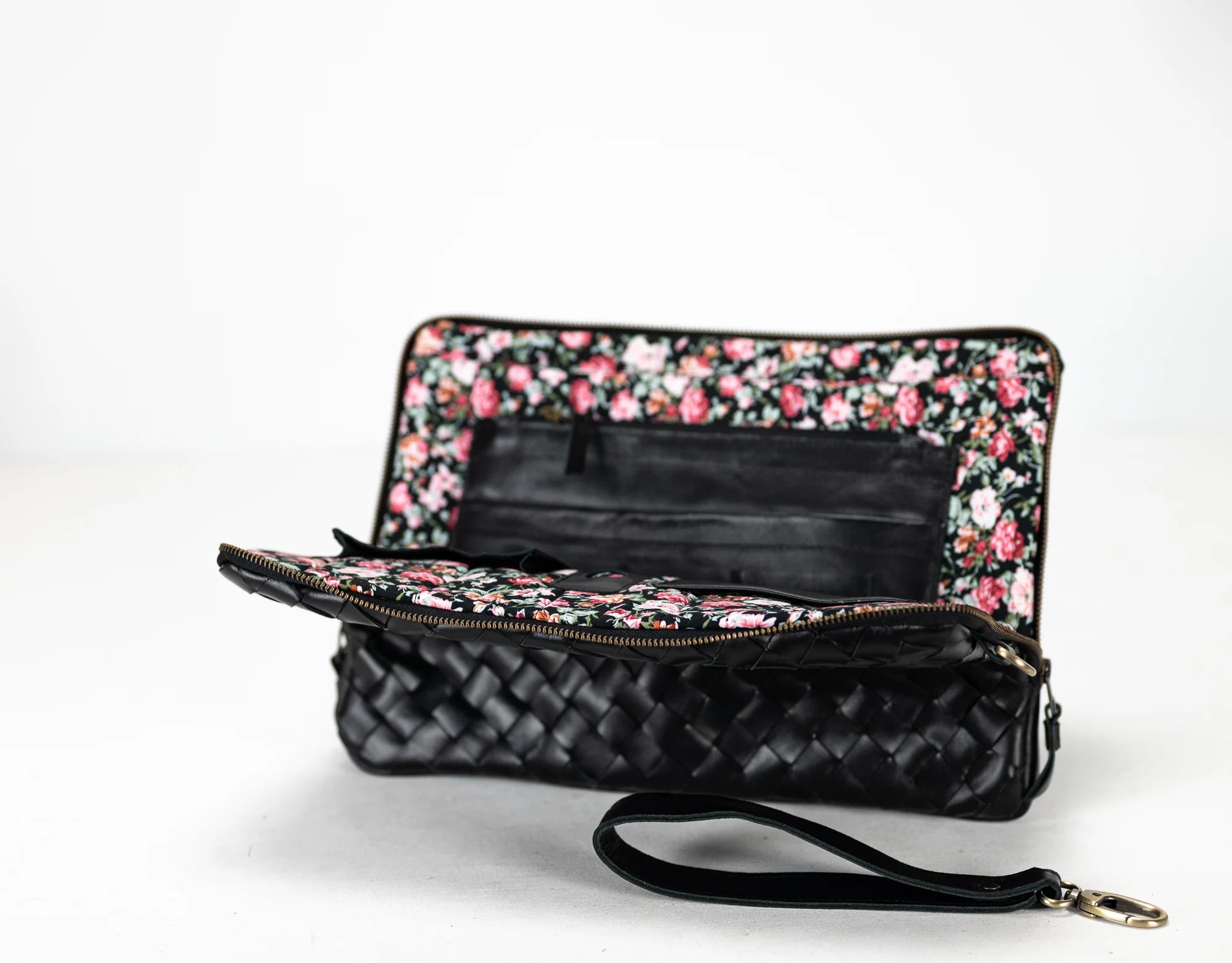 Floral-patterned clutch with a quilted black base on a white background